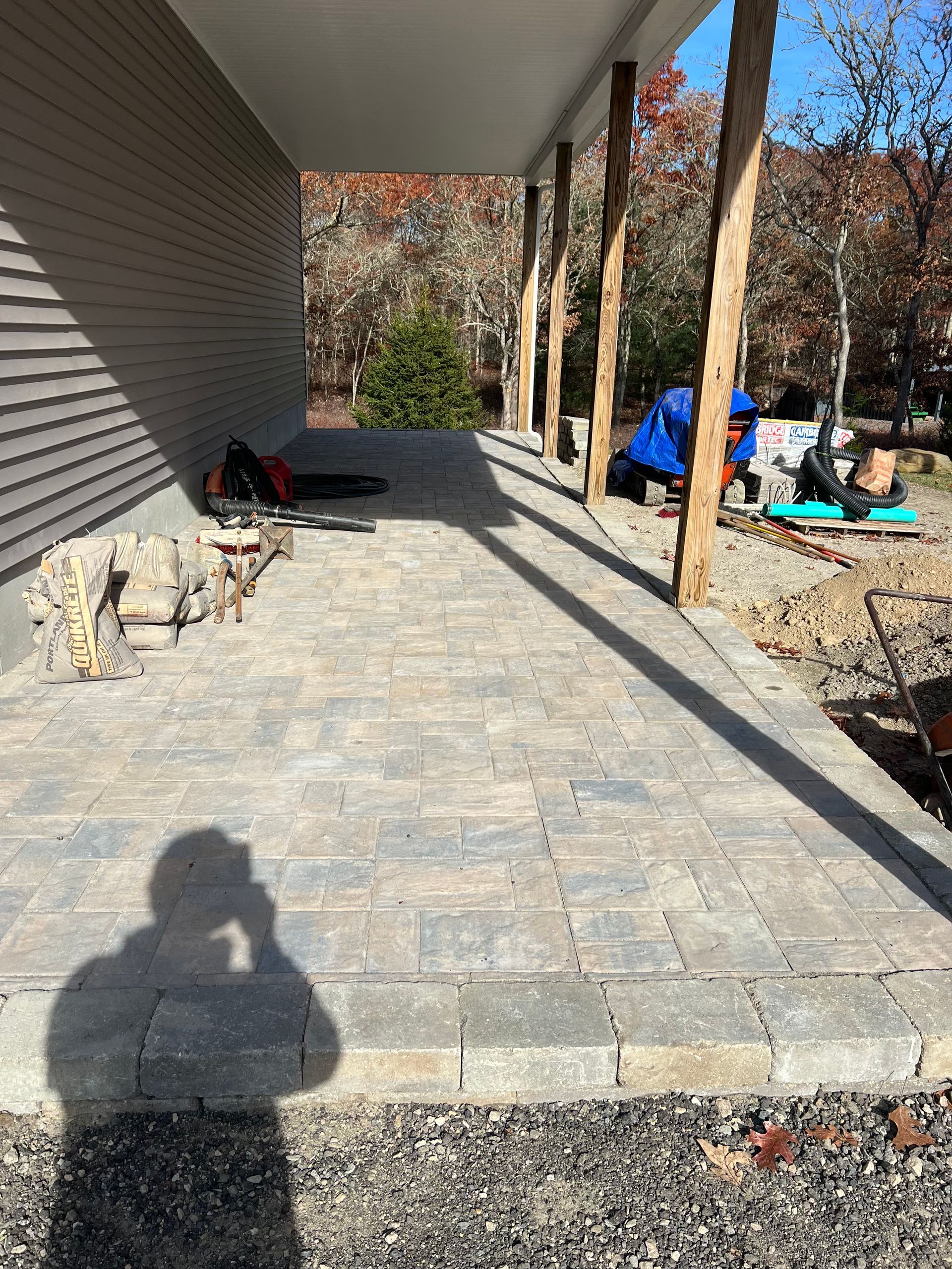 A shadow of a person is cast on a brick walkway in front of a house.
