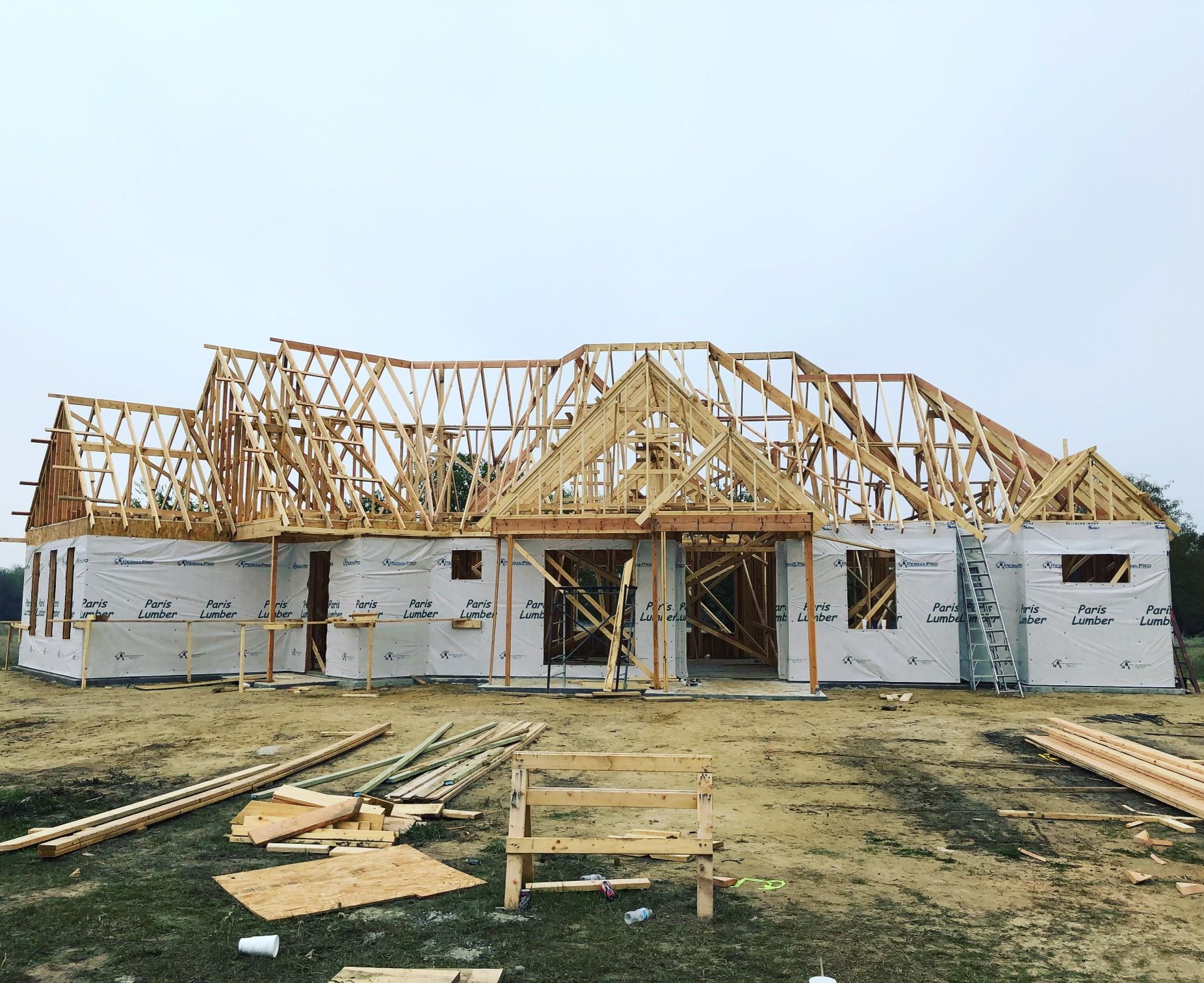 A large house is being built in a dirt field.