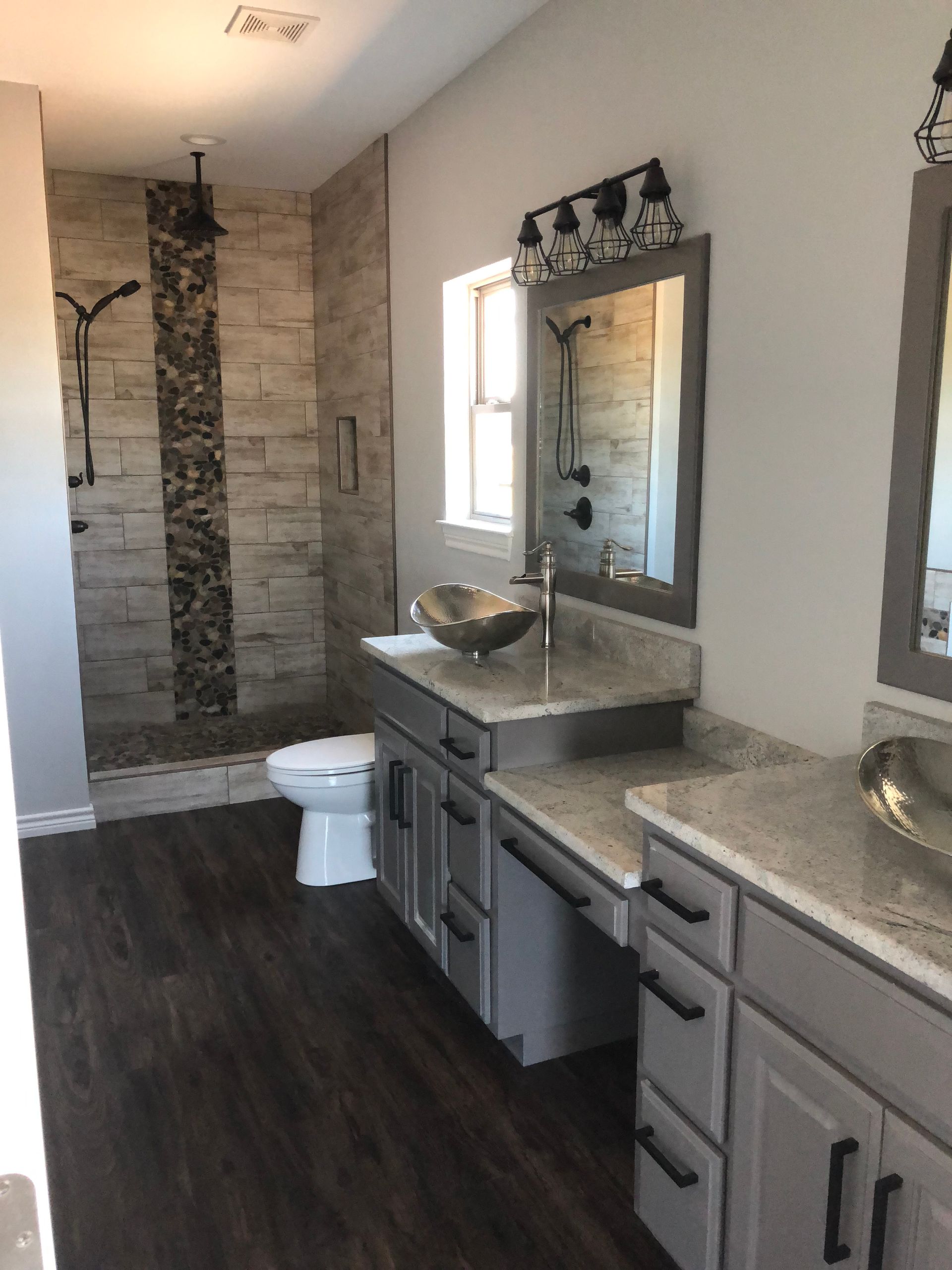A bathroom with a toilet , sink , mirror and shower.