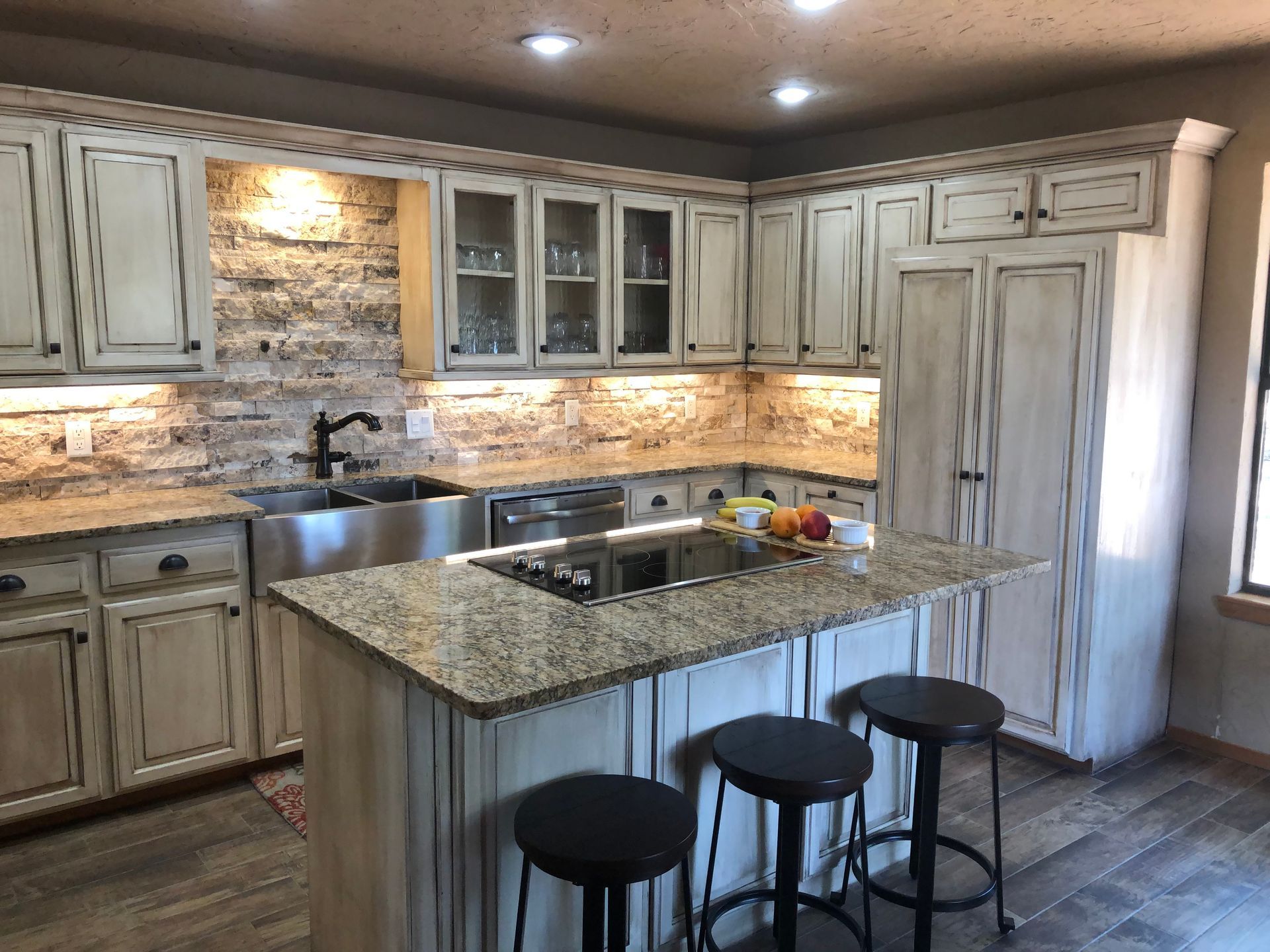 A kitchen with white cabinets , granite counter tops , stainless steel appliances and a large island.