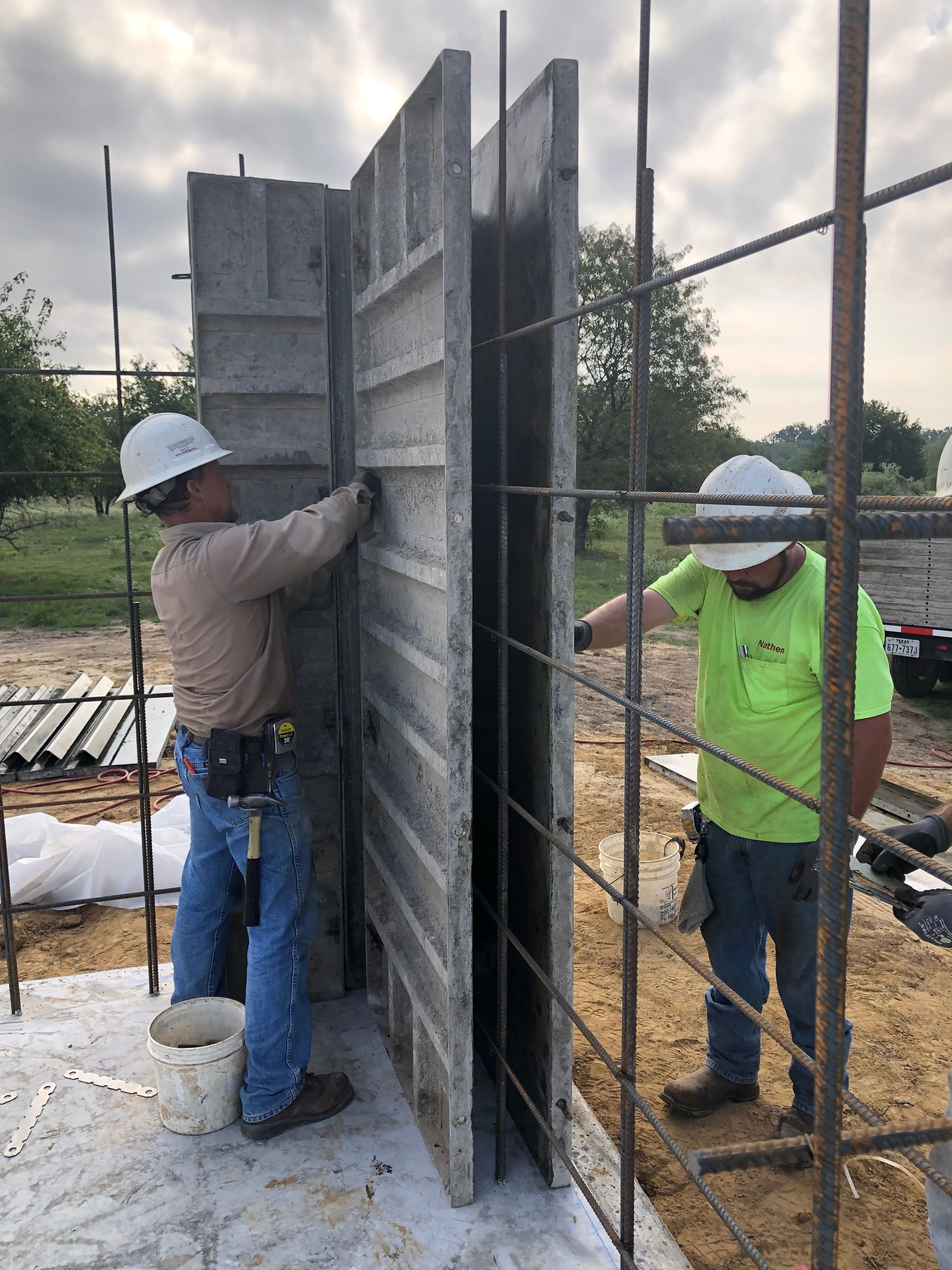 Two construction workers are working on a concrete wall