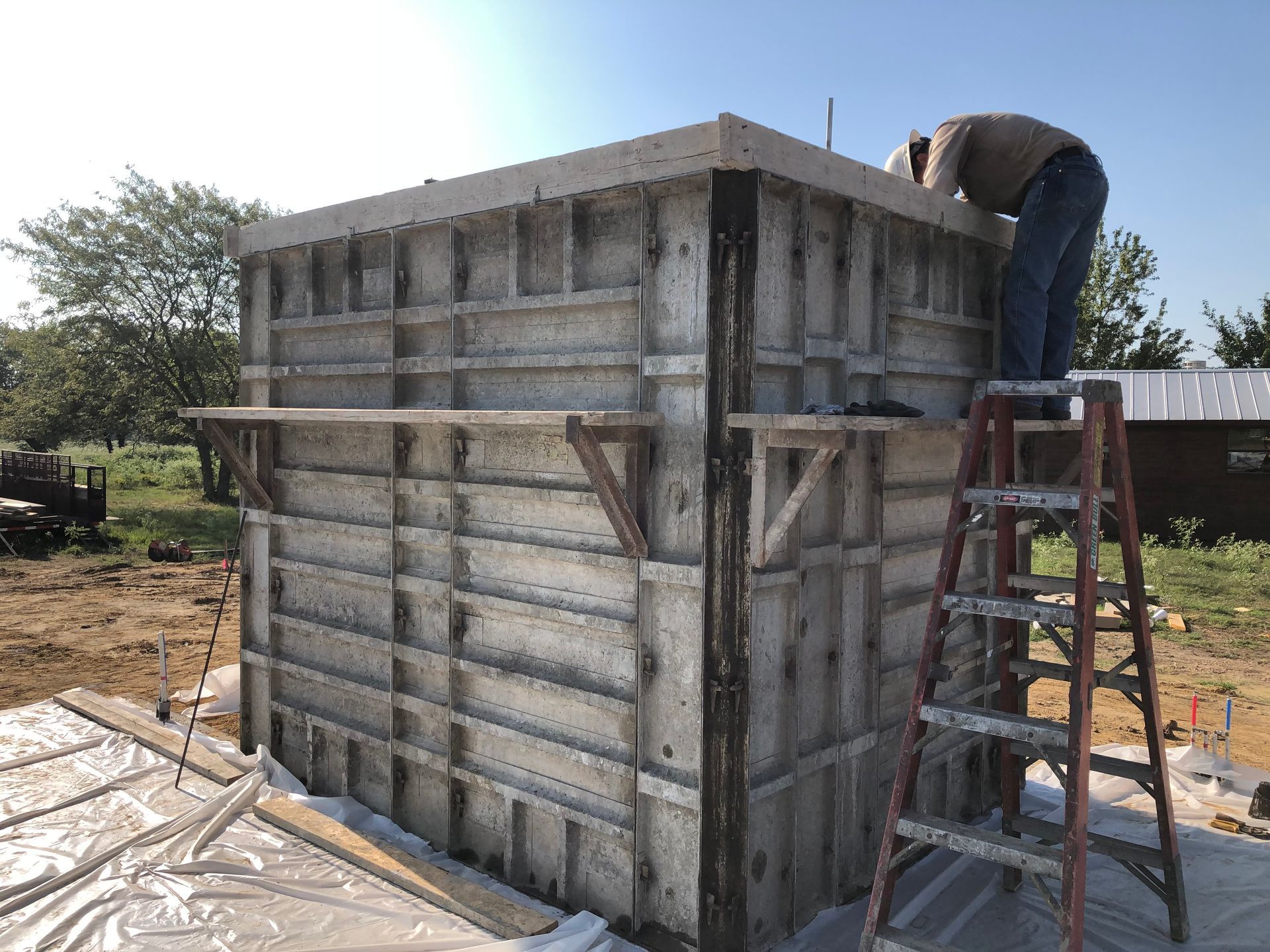 A man is standing on a ladder working on a concrete wall.