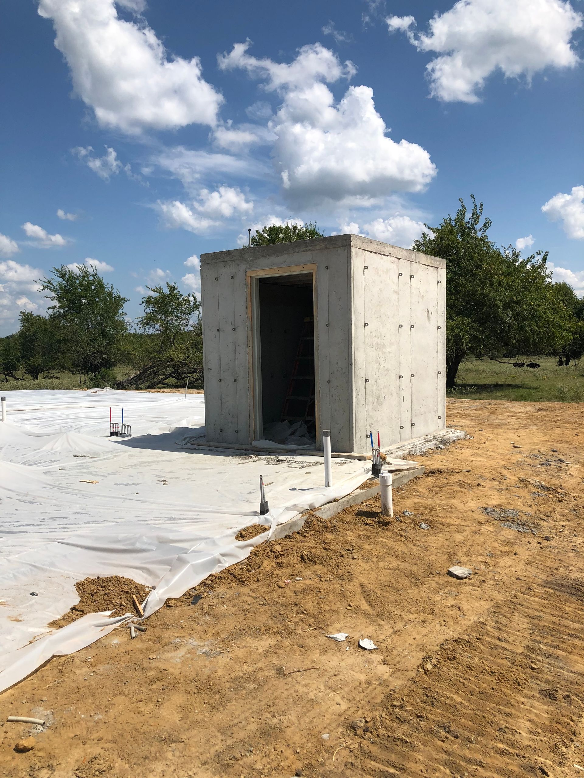 A small concrete building is sitting in the middle of a dirt field.