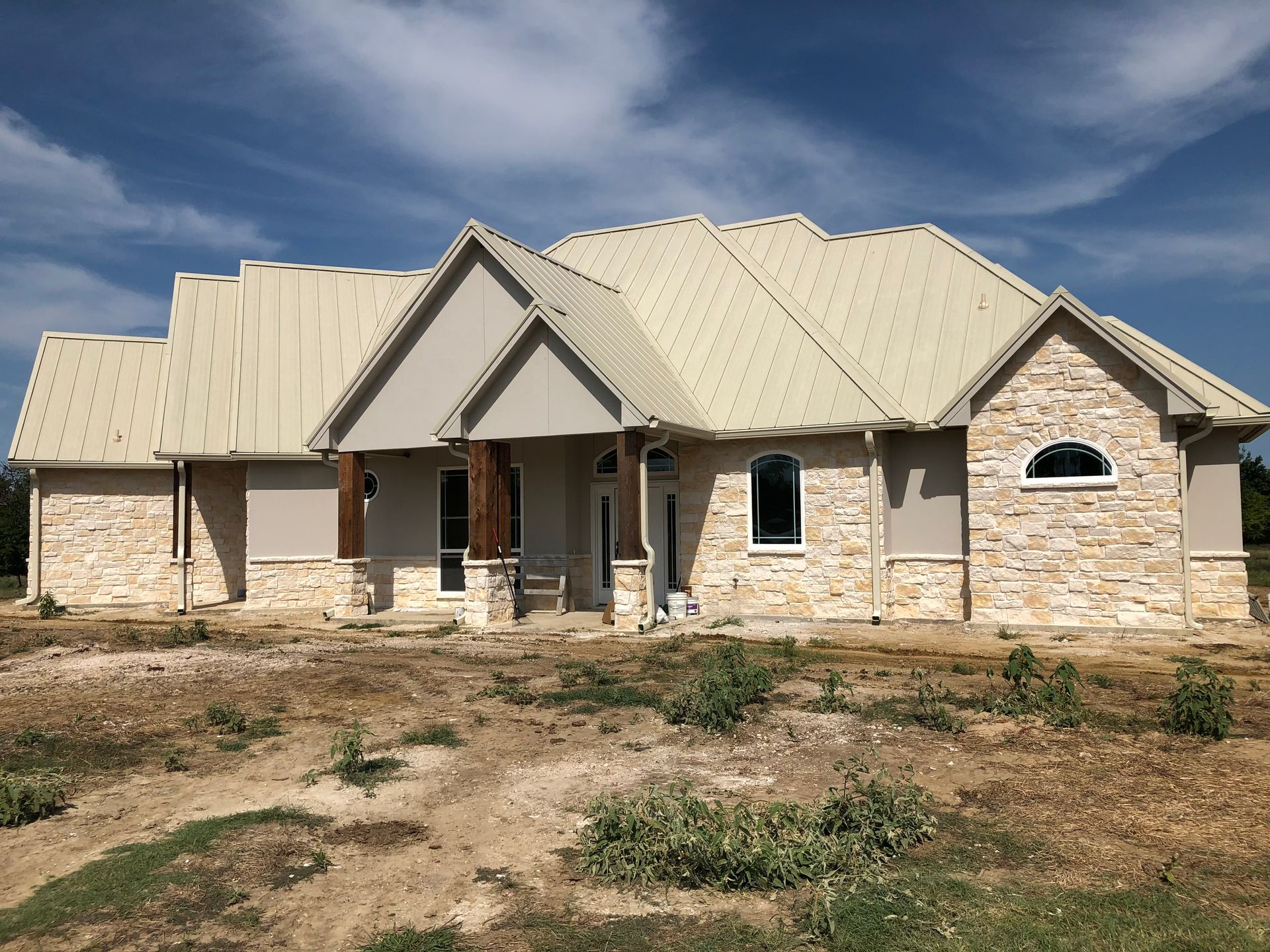 A large house with a metal roof is sitting in the middle of a field.
