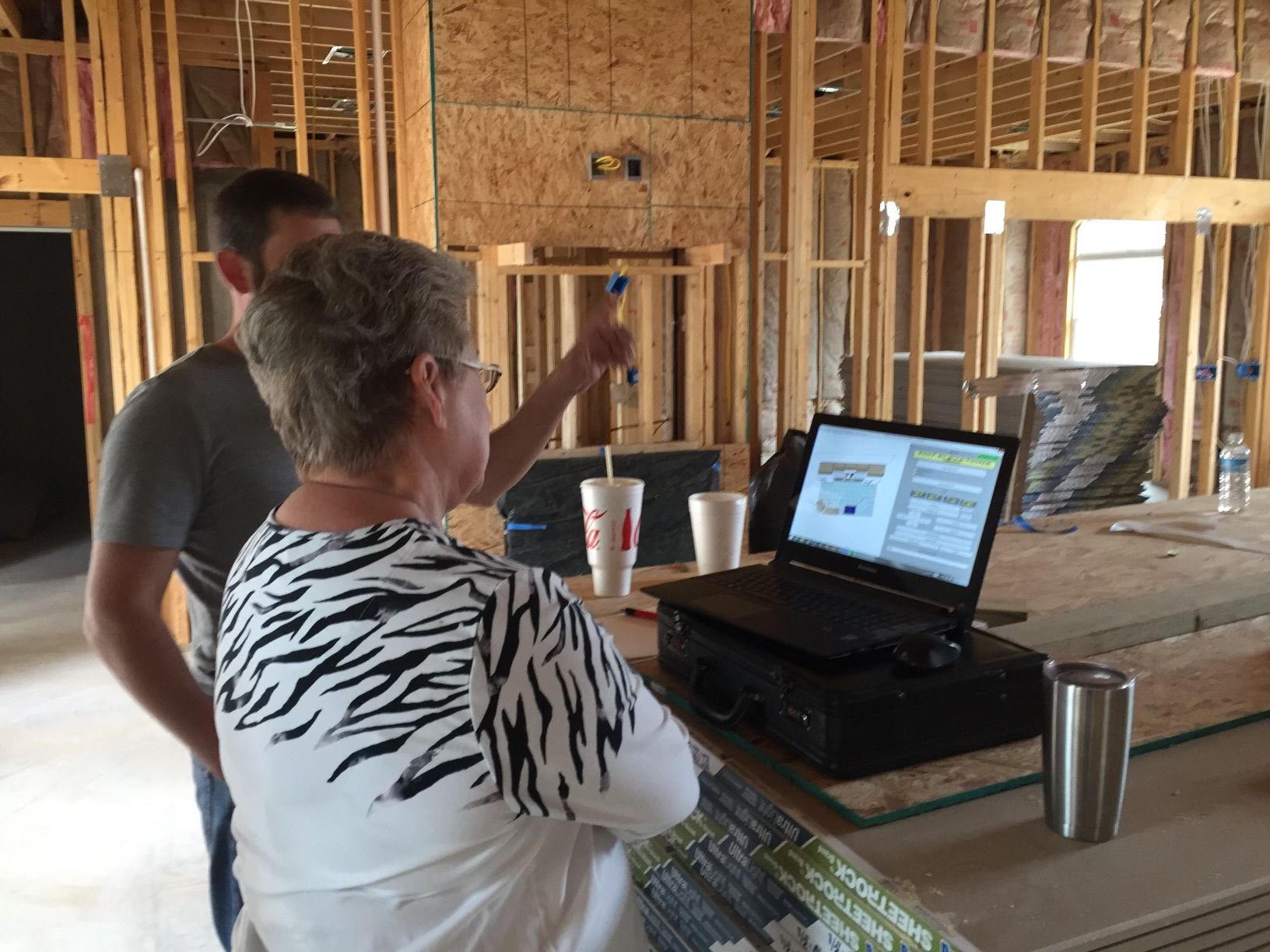 A man and a woman are looking at a laptop in a building under construction