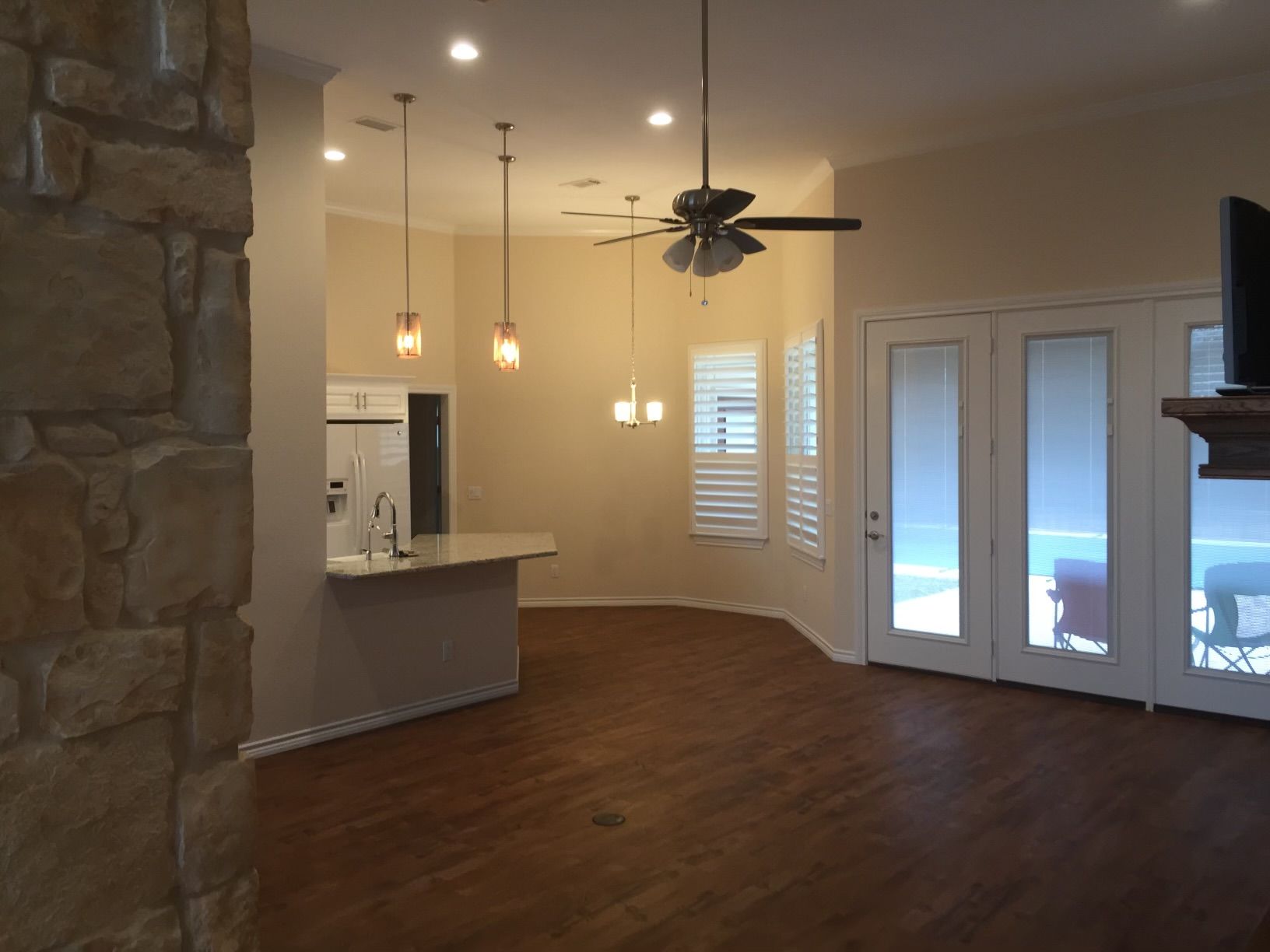 An empty living room with a ceiling fan and sliding glass doors