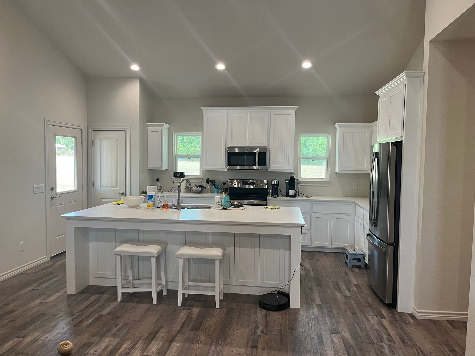 A kitchen with white cabinets , stainless steel appliances , and a large island.
