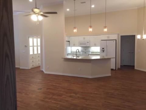 An empty kitchen with a ceiling fan and hardwood floors.