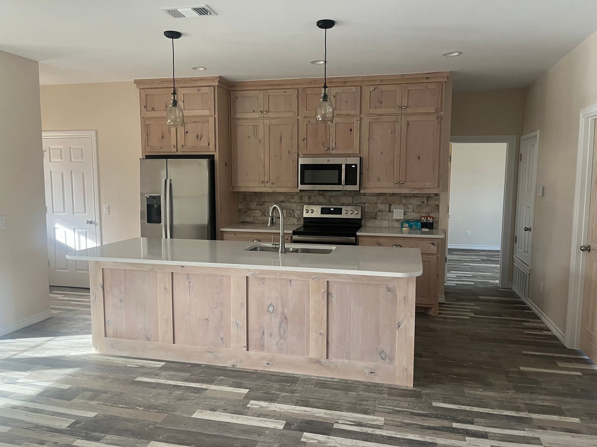 A kitchen with wooden cabinets , stainless steel appliances , and a large island.