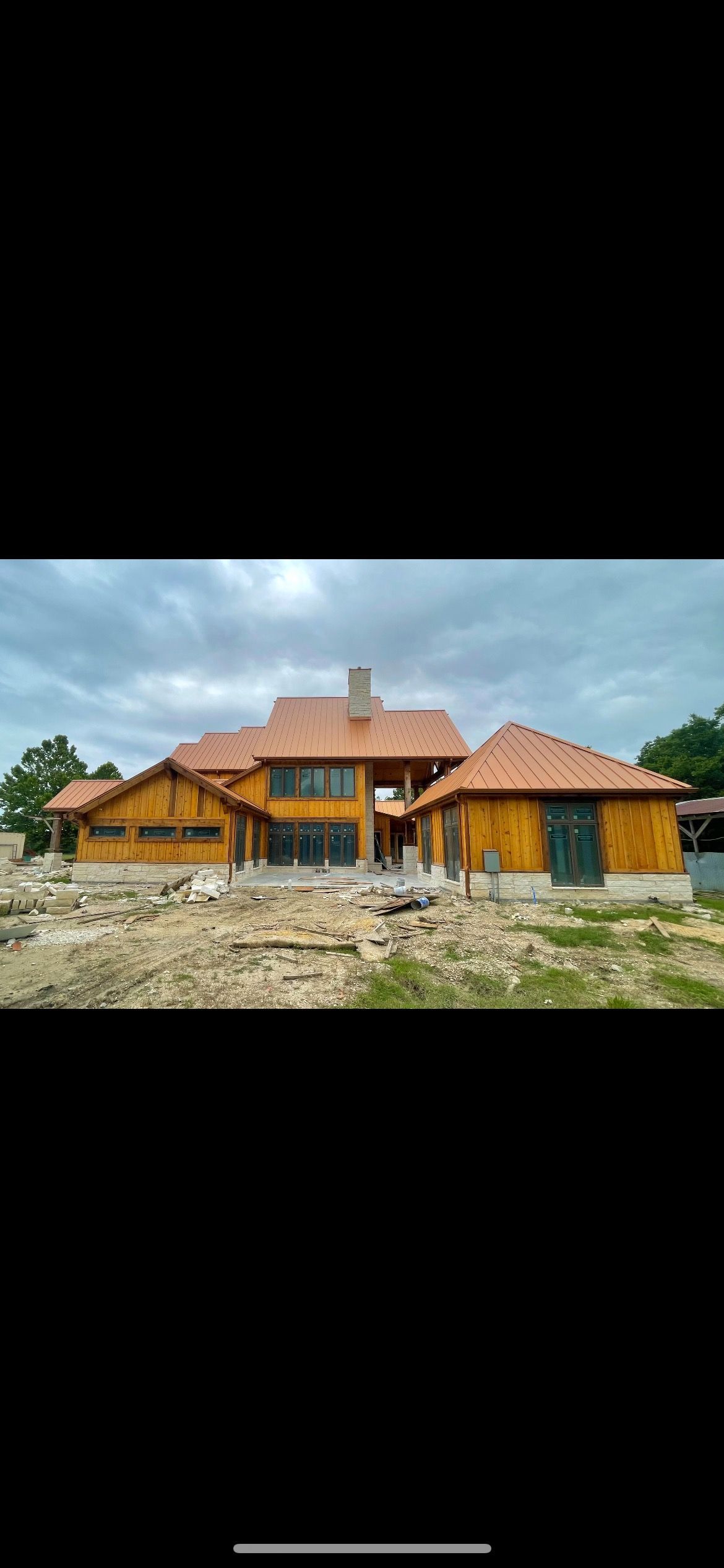 A large wooden house with a red tile roof is being built.