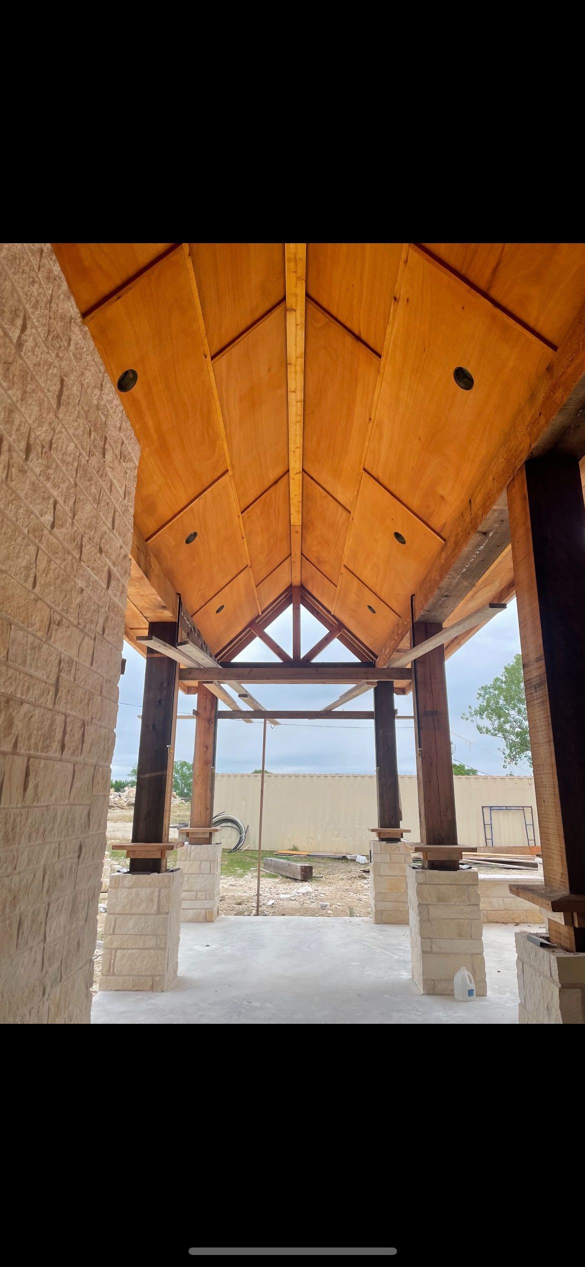A building under construction with a wooden ceiling and pillars.
