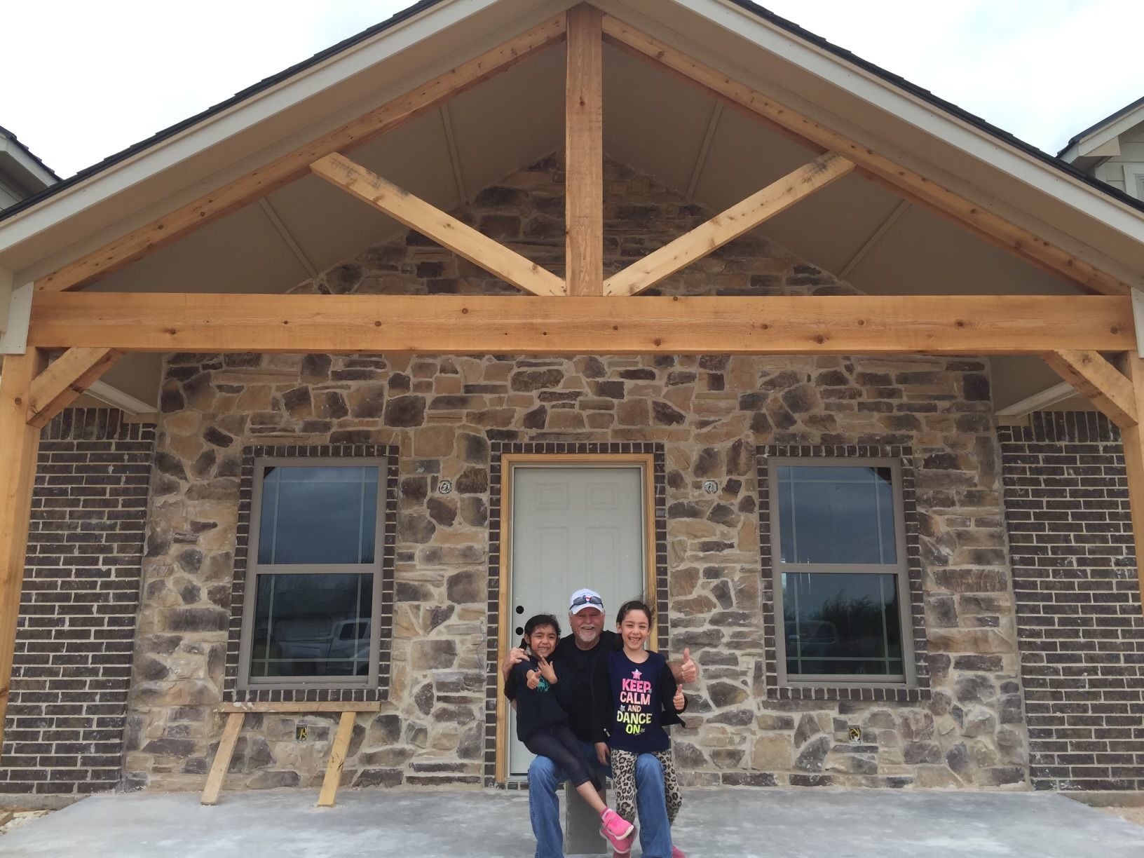 A family is posing for a picture in front of a stone house
