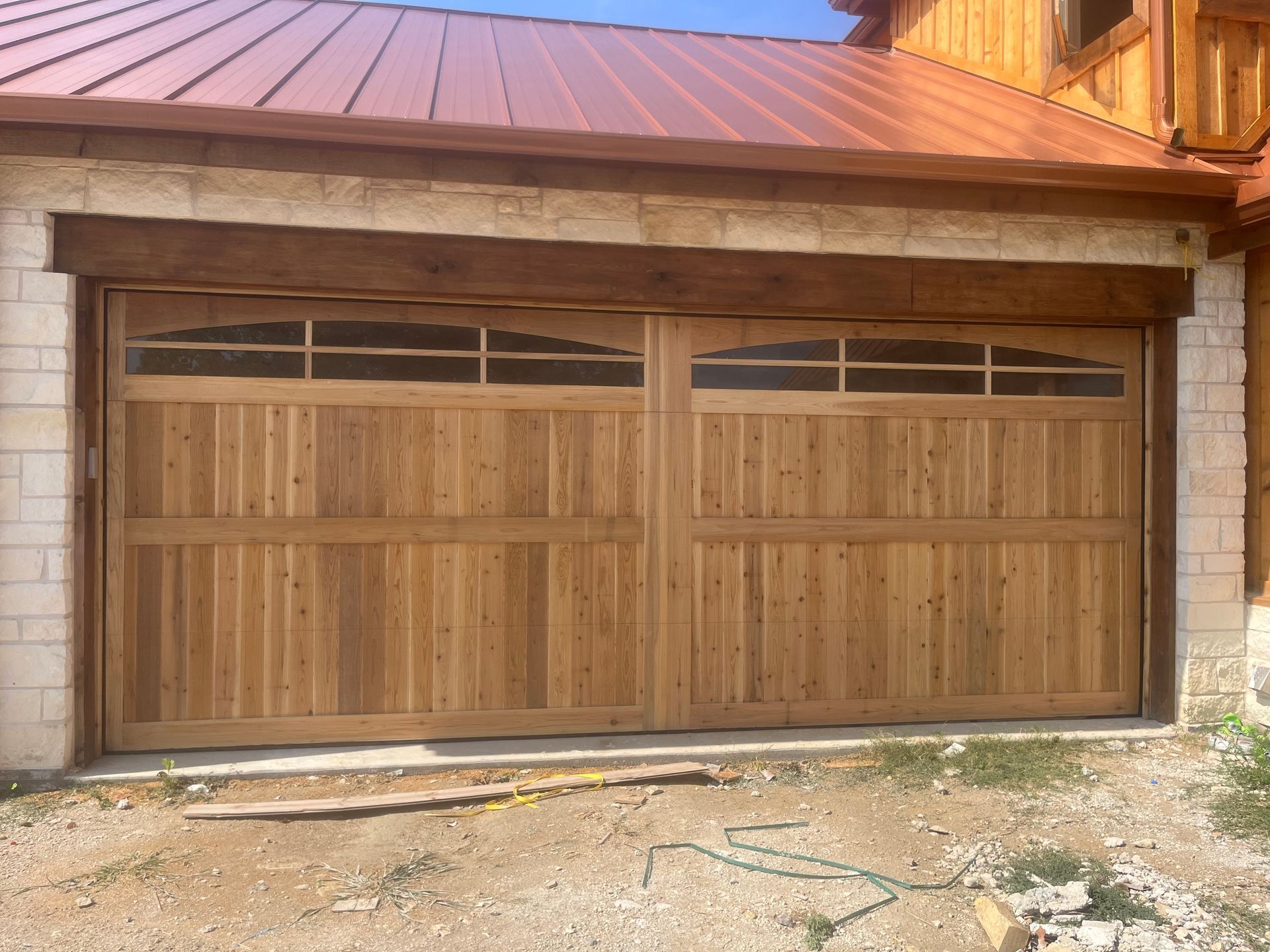 A wooden garage door is sitting in front of a brick building.