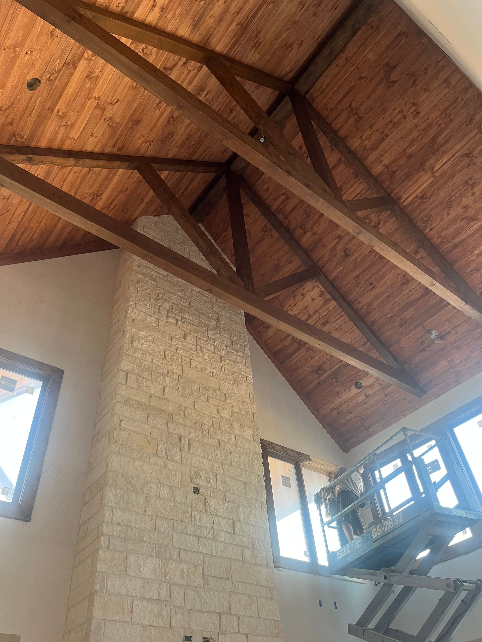 A room with a brick fireplace and wooden beams on the ceiling.