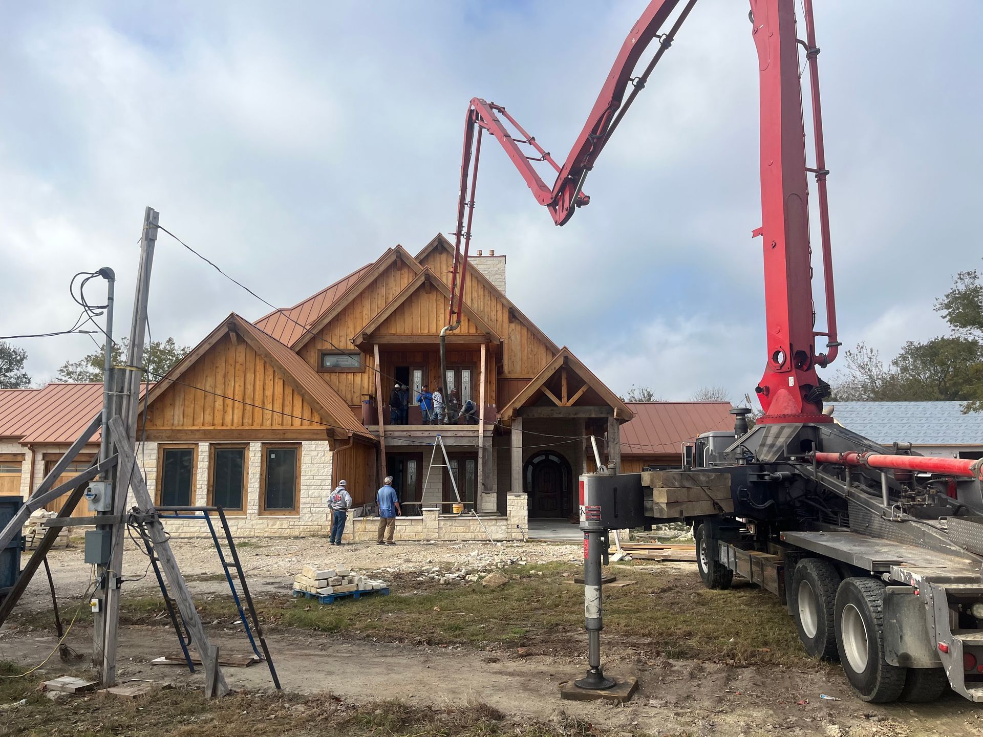 A large house is being built with a concrete pump in front of it.