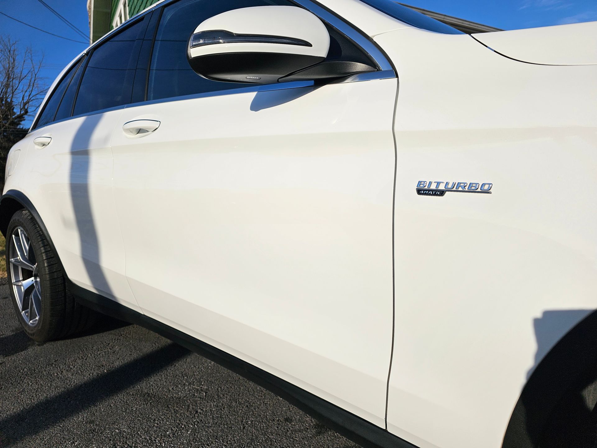 White Mercedes SUV with AMG badge, parked on asphalt.