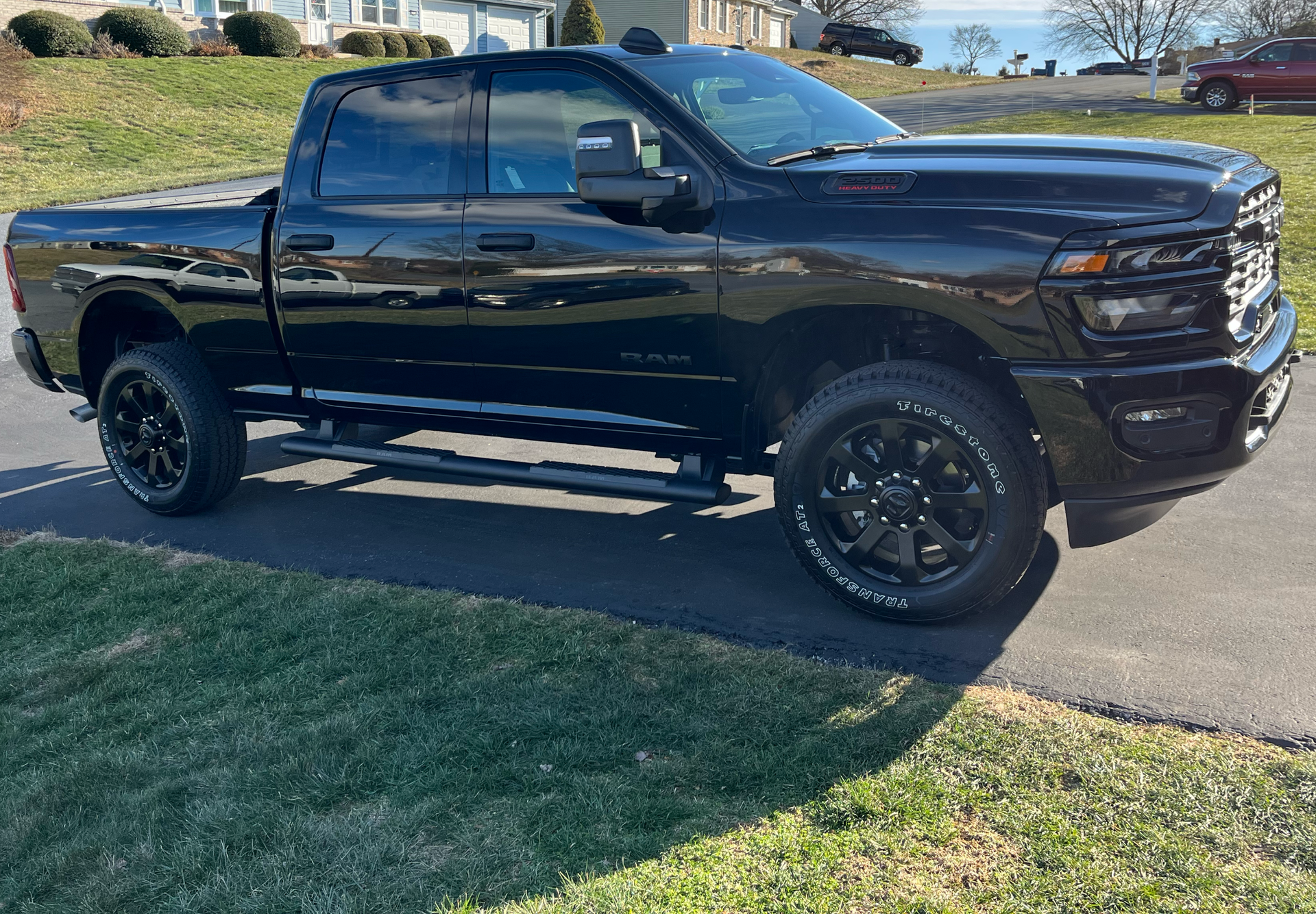 Black Ram pickup truck parked on asphalt driveway, with green grass surrounding it.