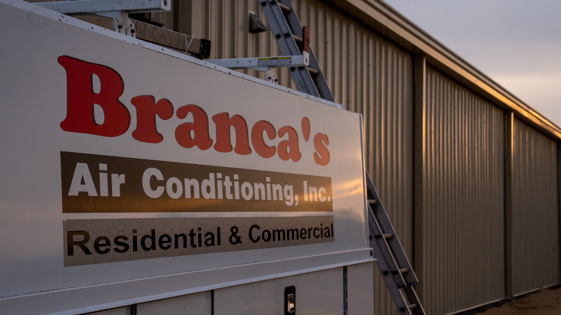 Branca’s Air Conditioning, Inc. sign on a building exterior at sunset