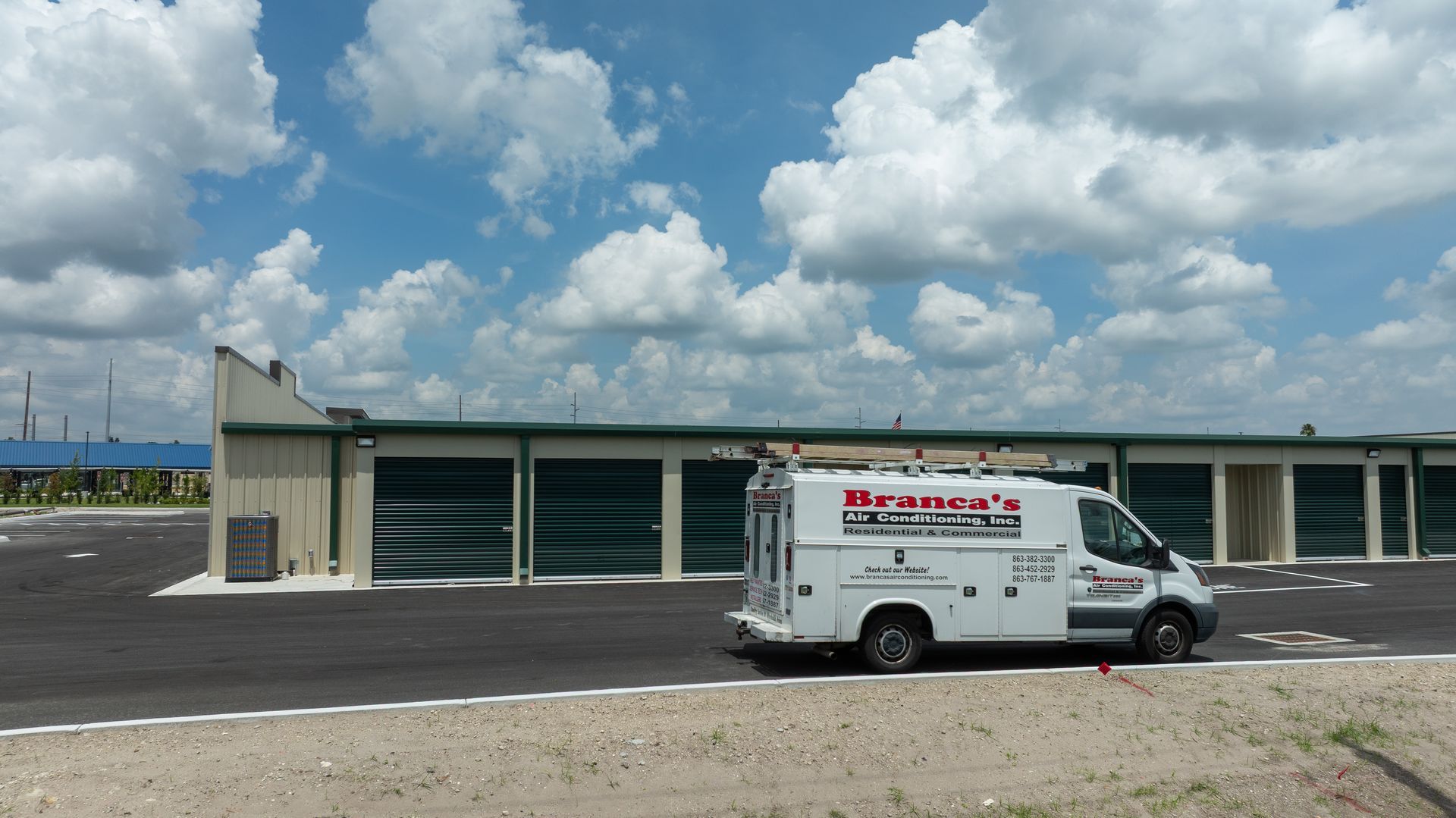 White service van parked in front of storage units under a cloudy sky