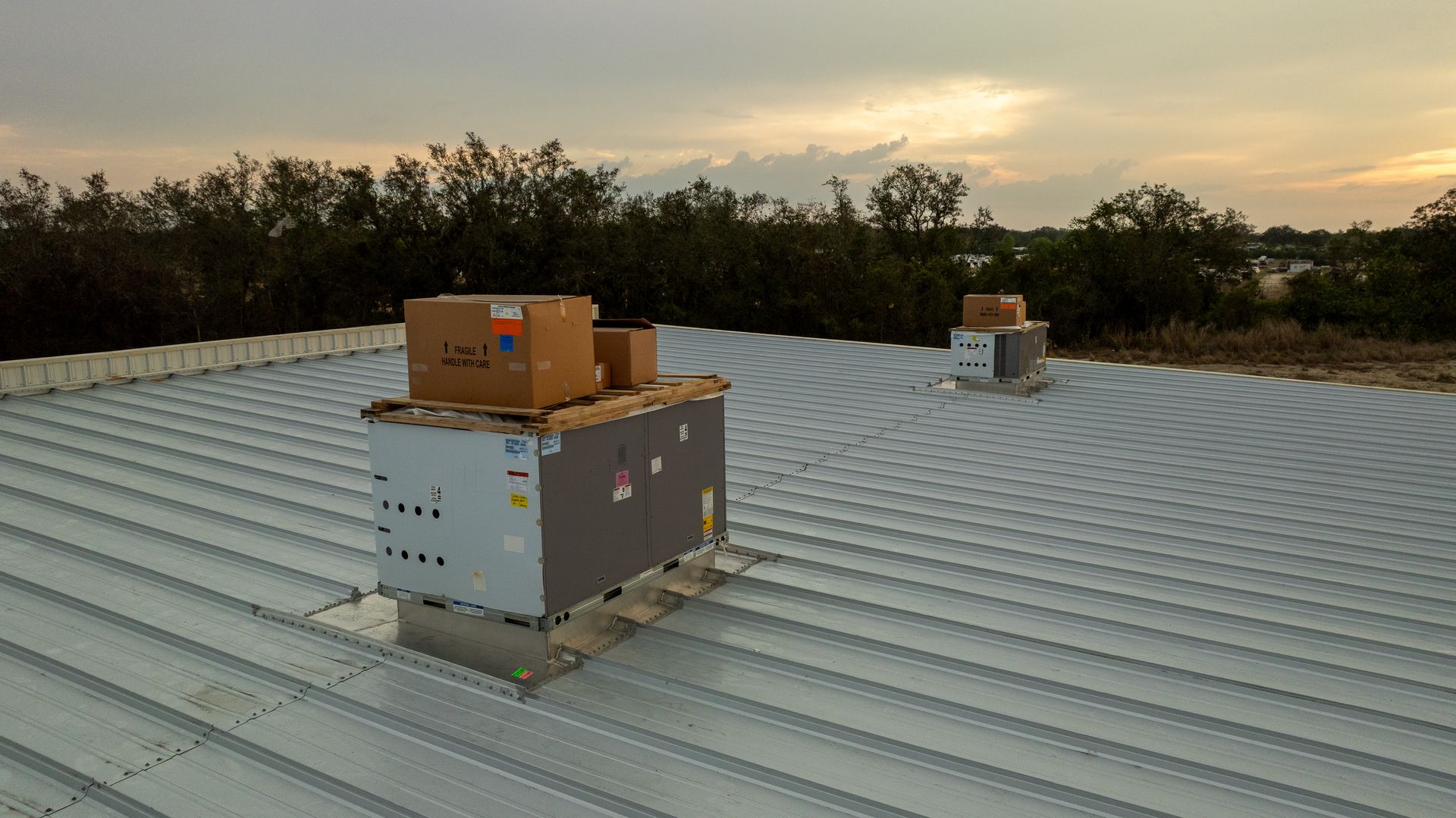 Two rooftop utility units on a corrugated metal roof at dusk