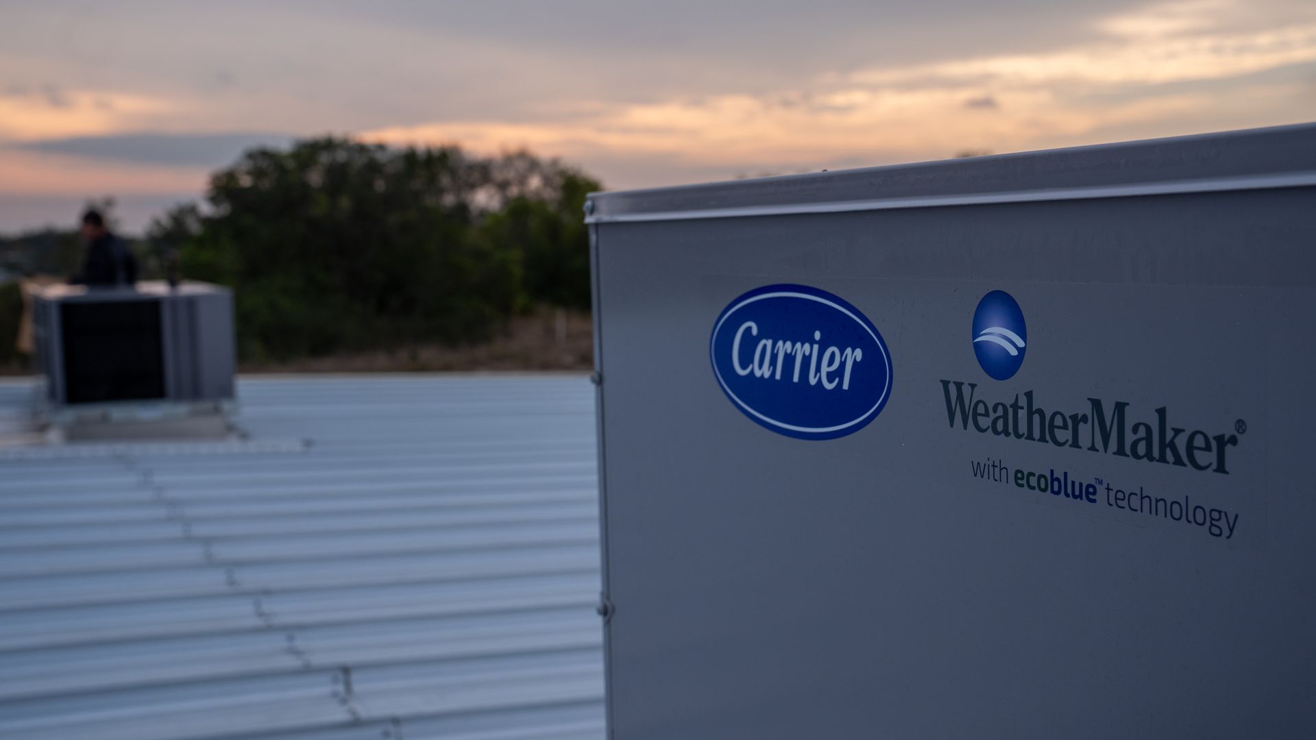 Carrier WeatherMaker rooftop HVAC unit at sunset on a flat roof