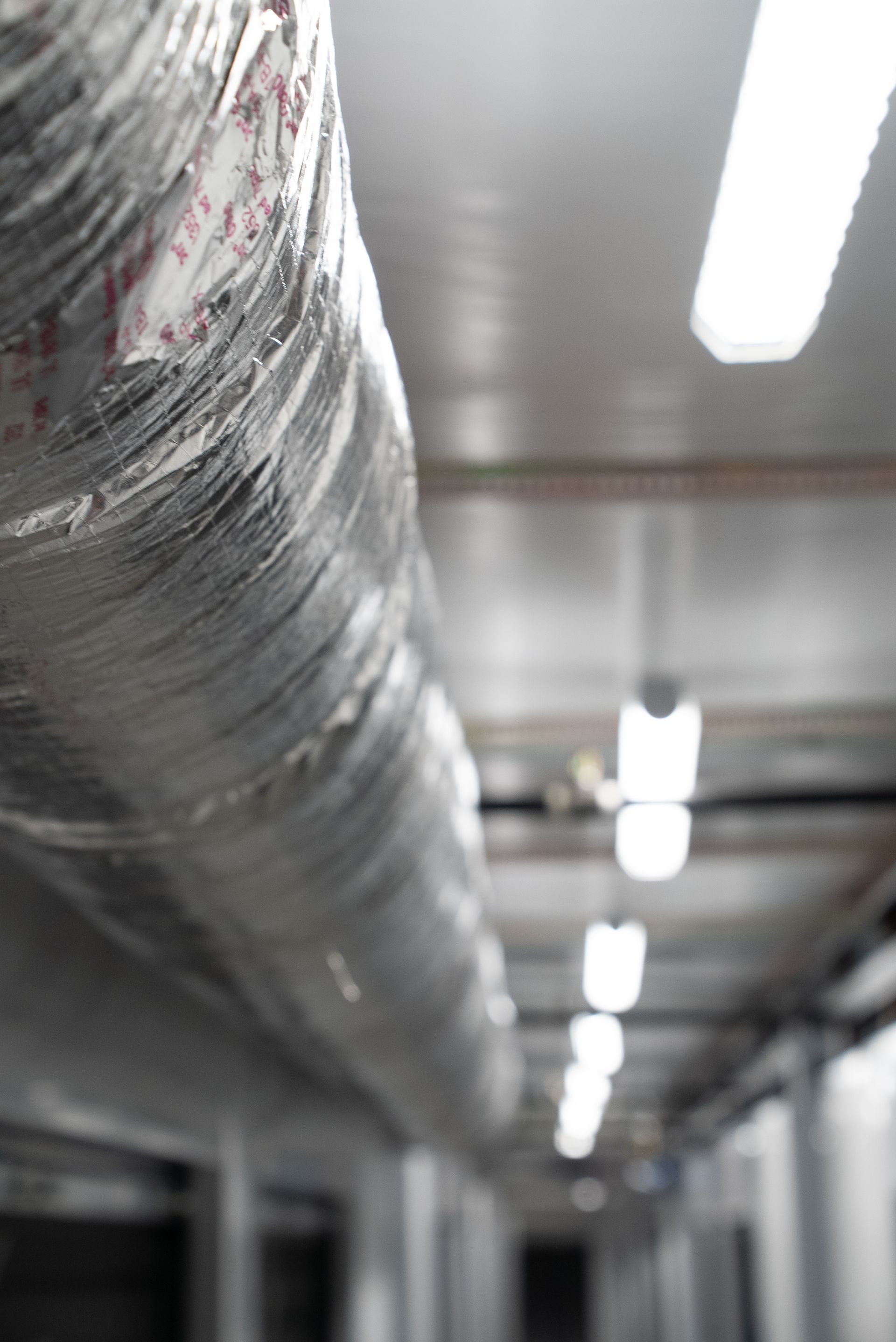Industrial hallway with exposed ductwork and bright overhead lights, blurred in the background