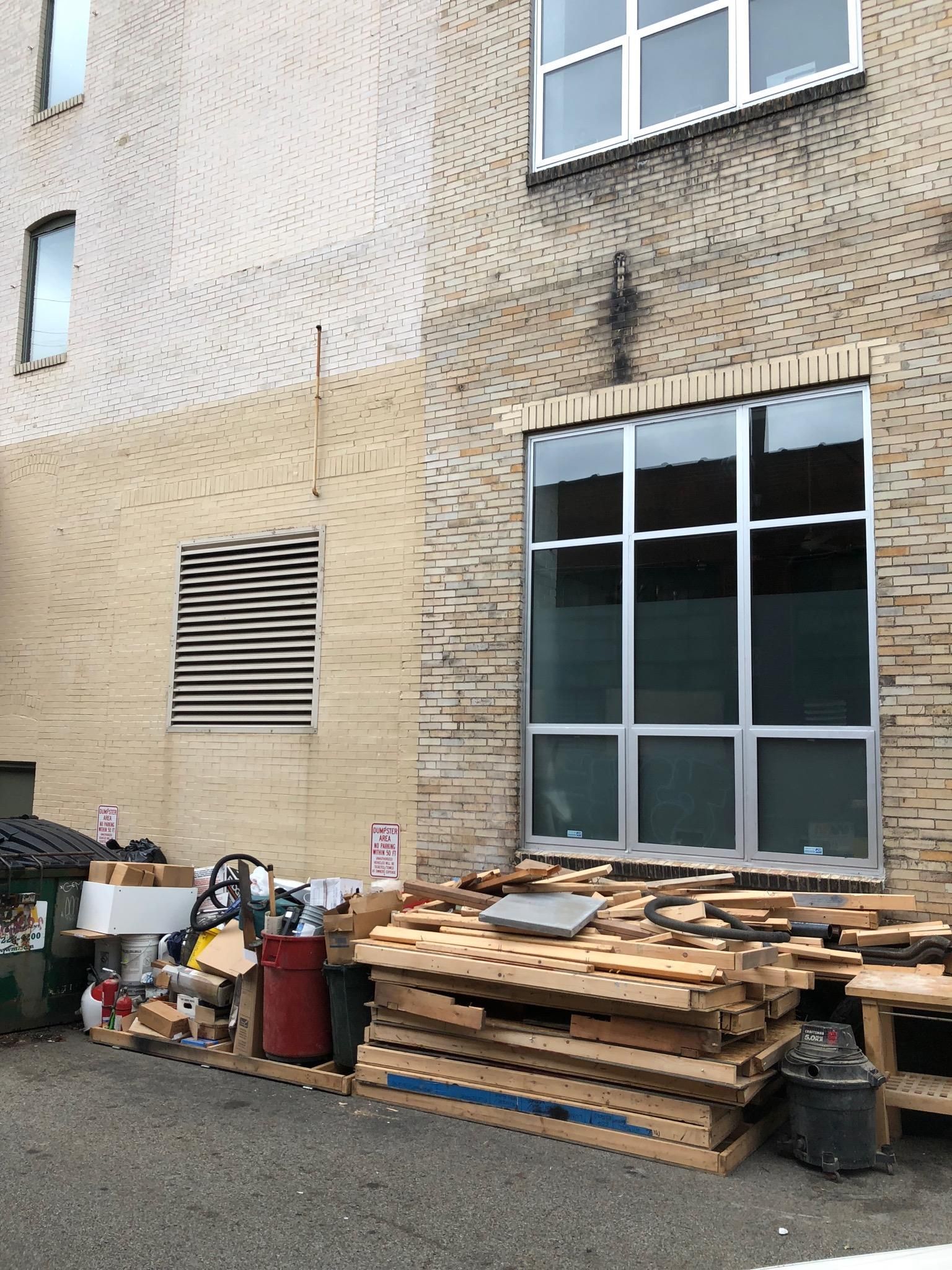 A pile of wooden pallets is sitting in front of a brick building.