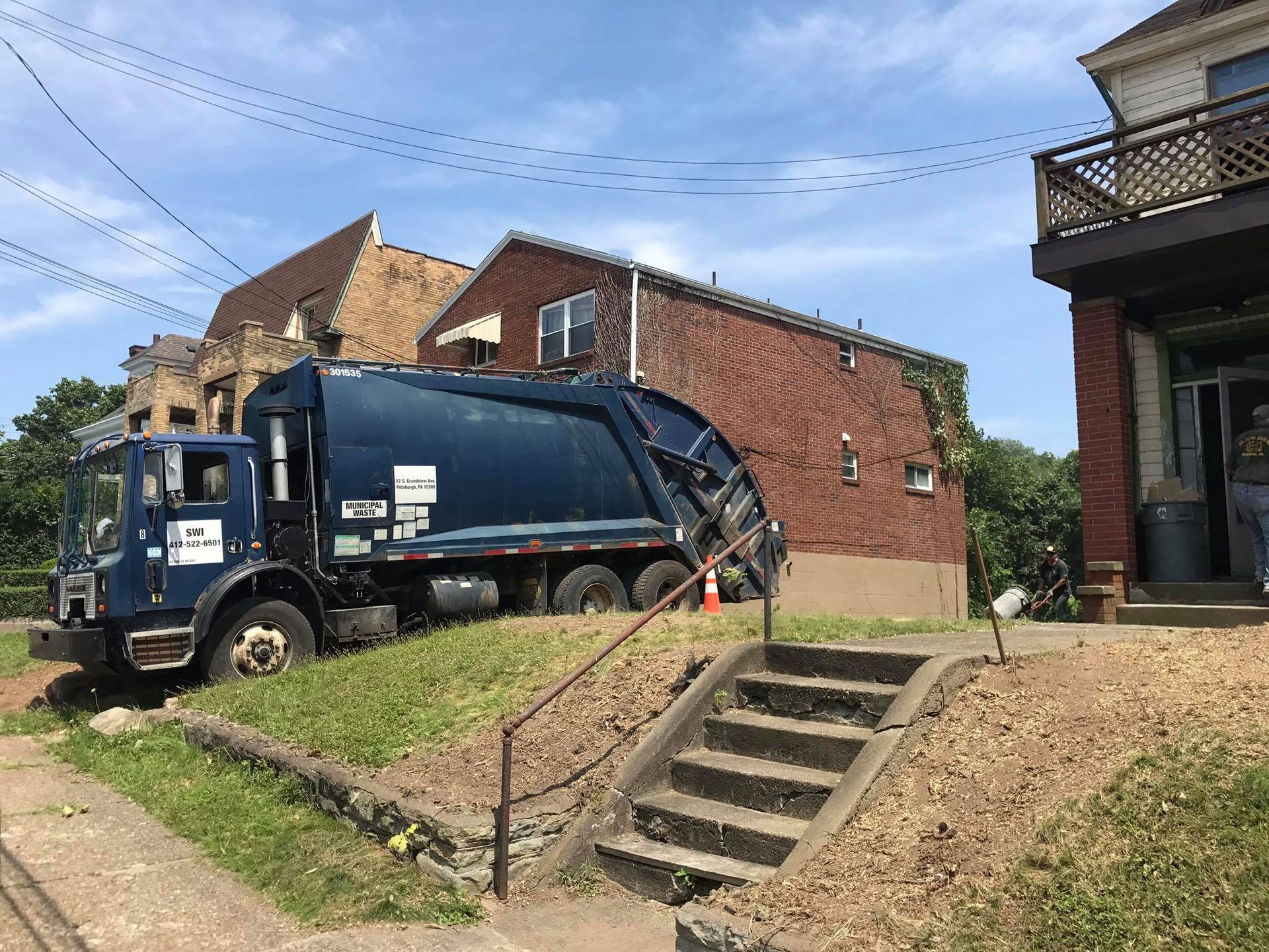 A garbage truck is parked in front of a brick building.