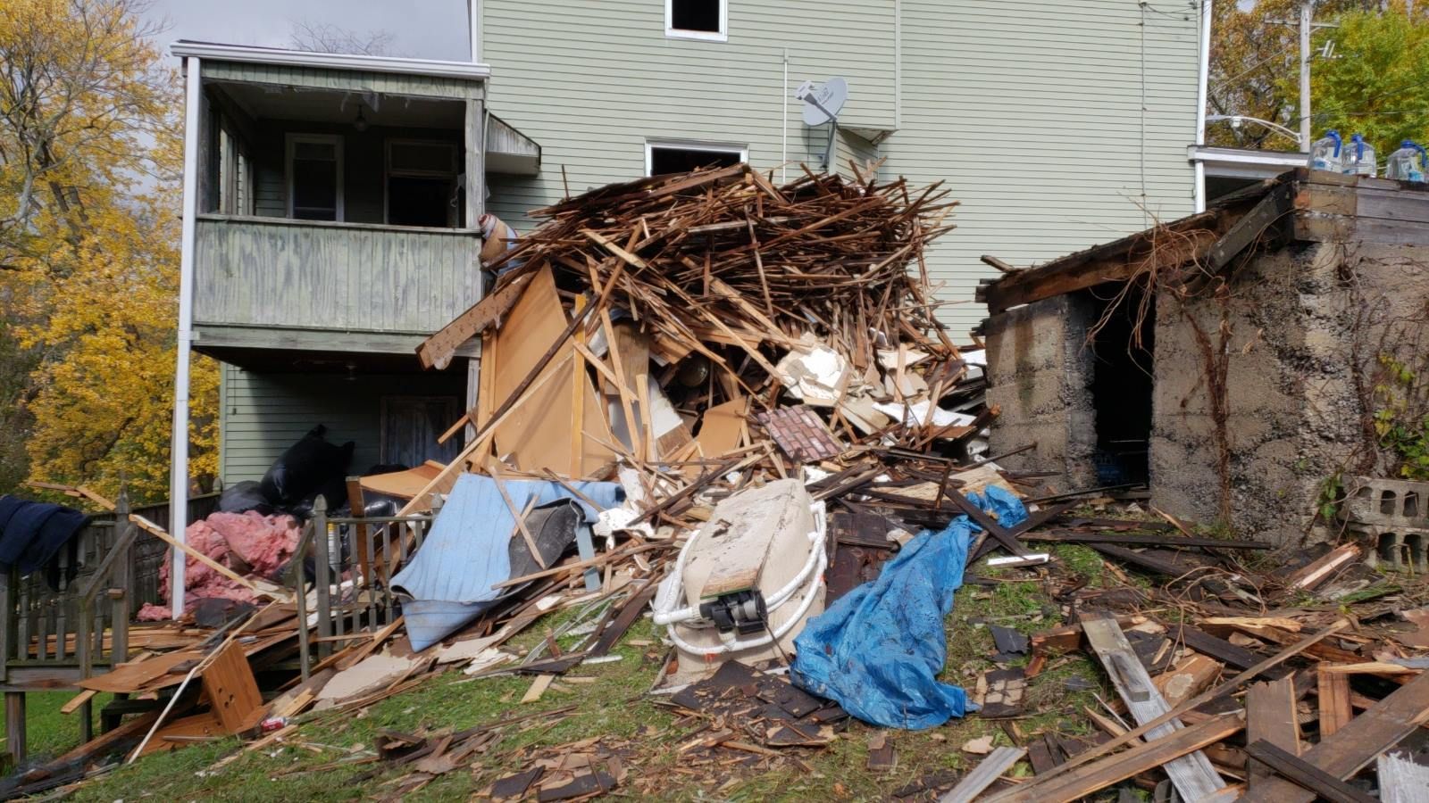 A house that has been demolished is sitting on top of a pile of wood.