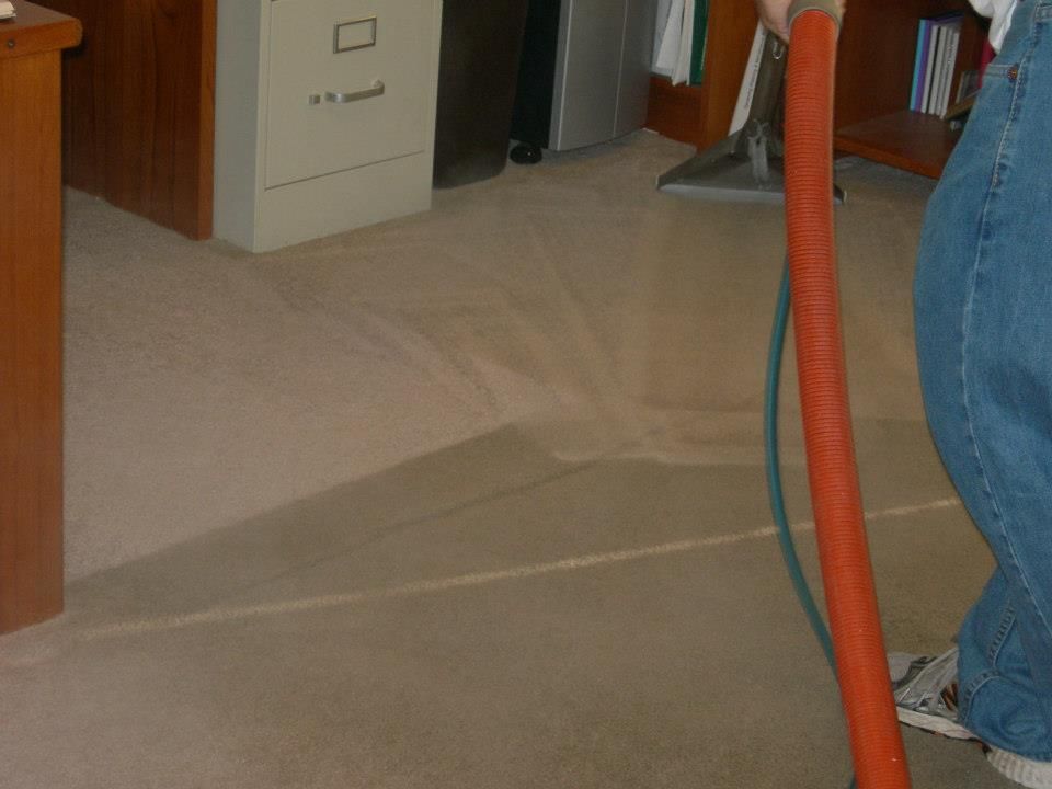 A person is cleaning a carpet with a vacuum cleaner.