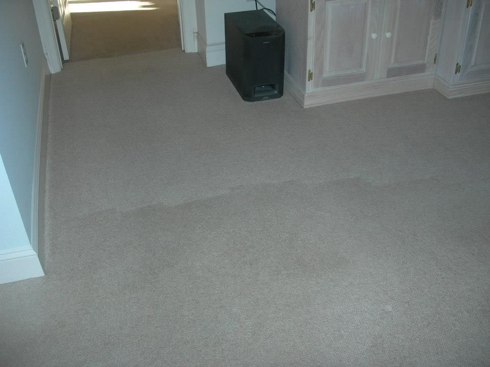 A room with a carpeted floor and a subwoofer in the corner.