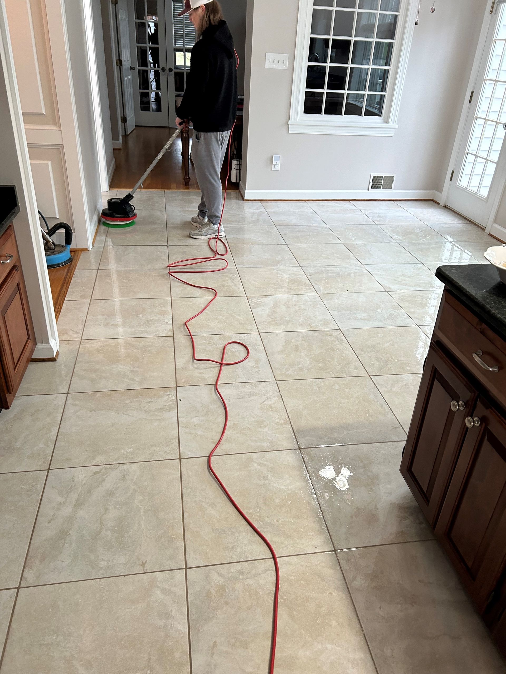 A person is cleaning a tile floor with a mop.