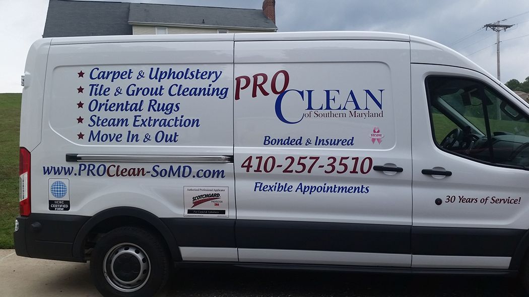 A white van that says pro clean on the side is parked in front of a building.