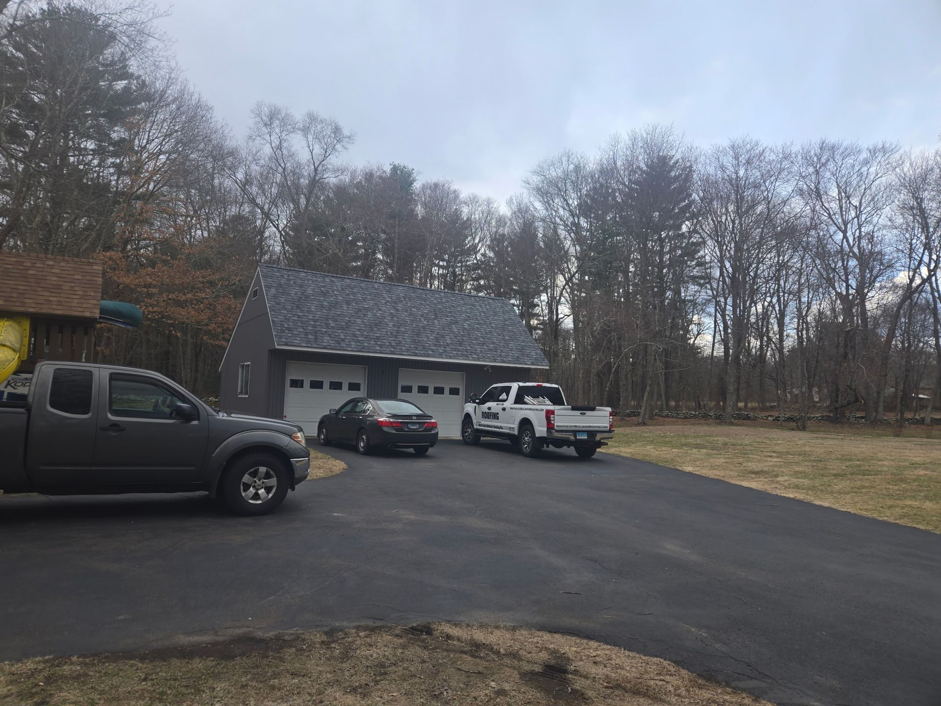 Two trucks are parked in a driveway in front of a garage.