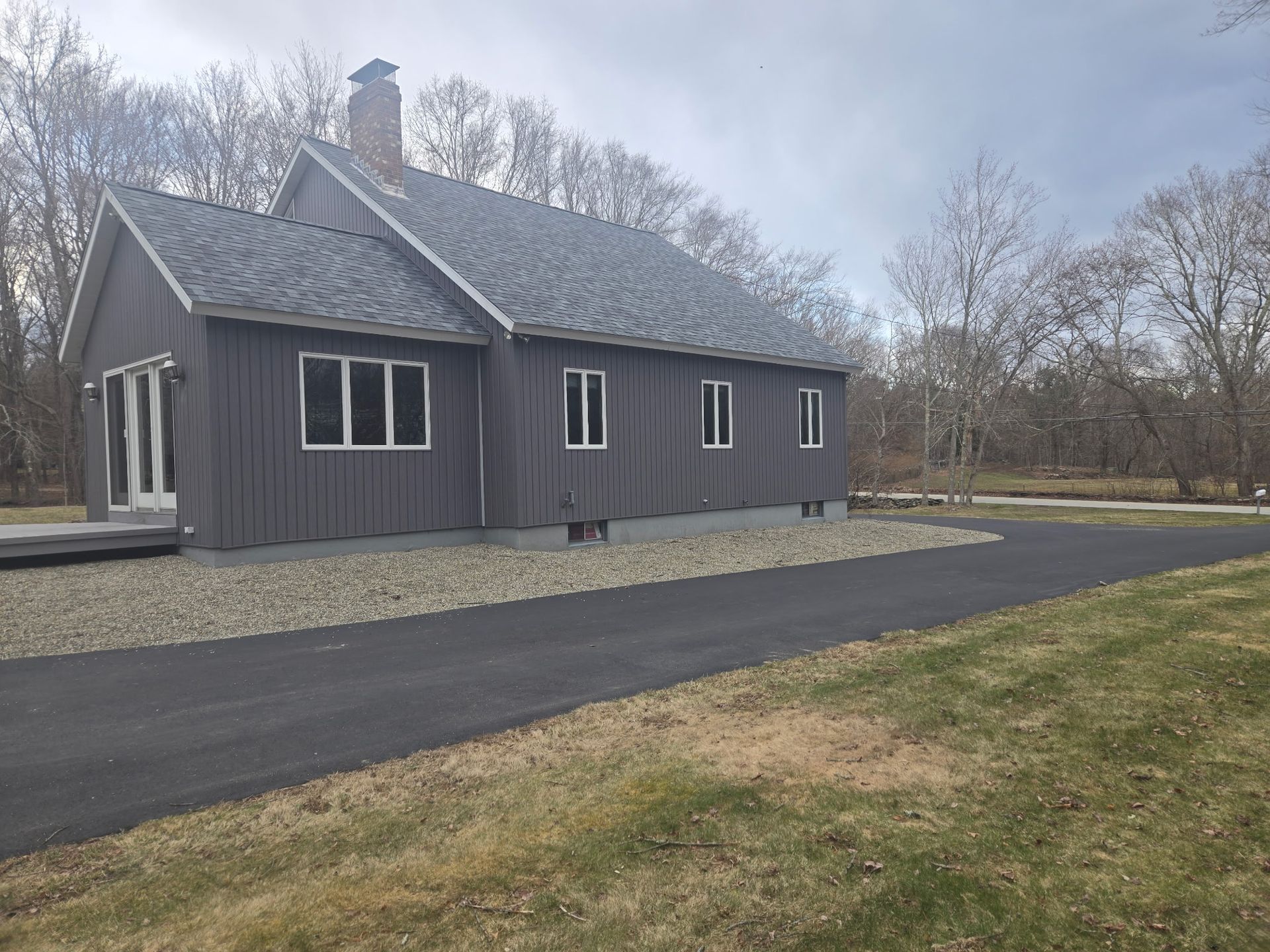 A large house with a lot of windows is sitting on top of a lush green field.