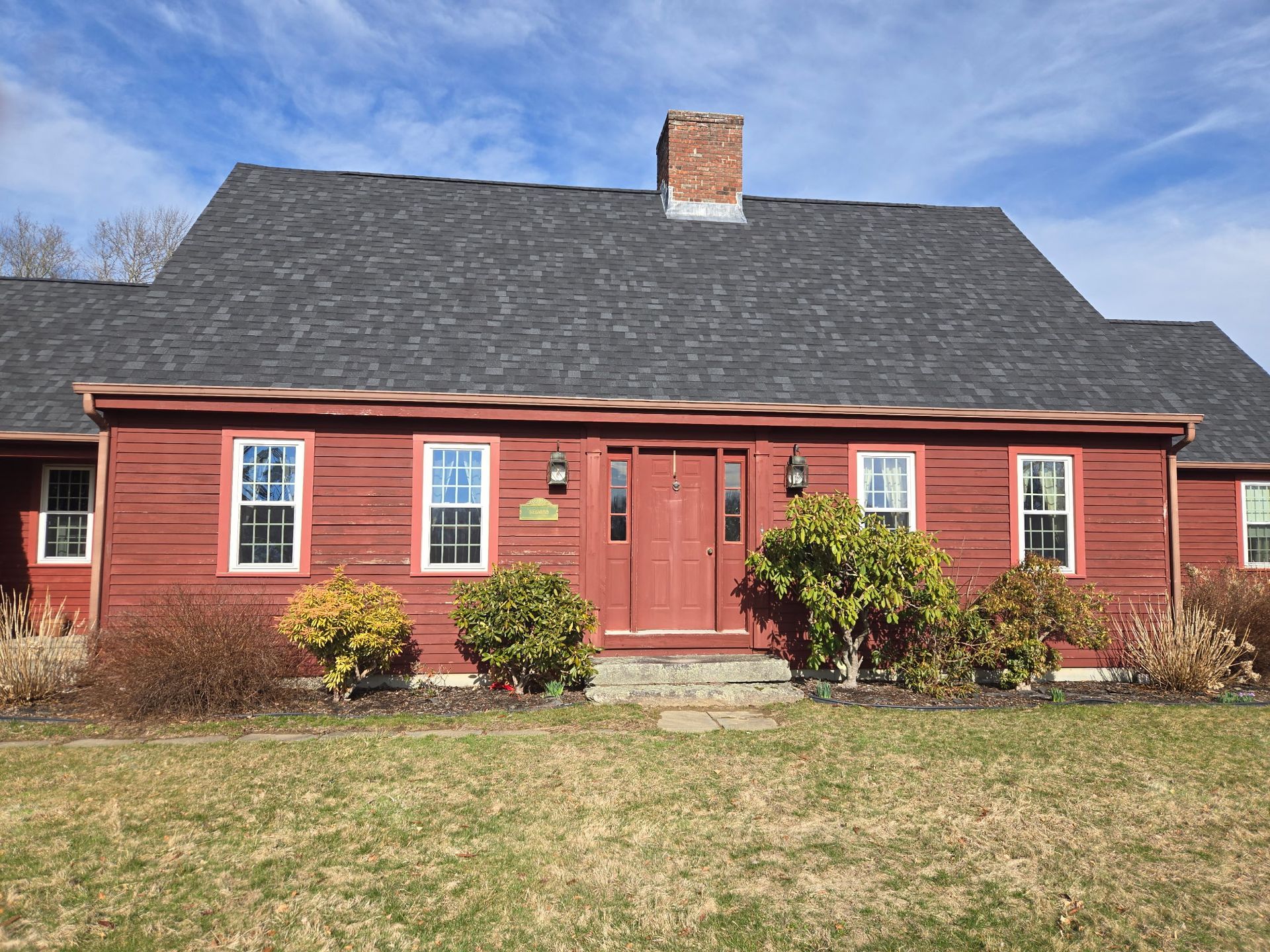 A red house with a black roof and a chimney