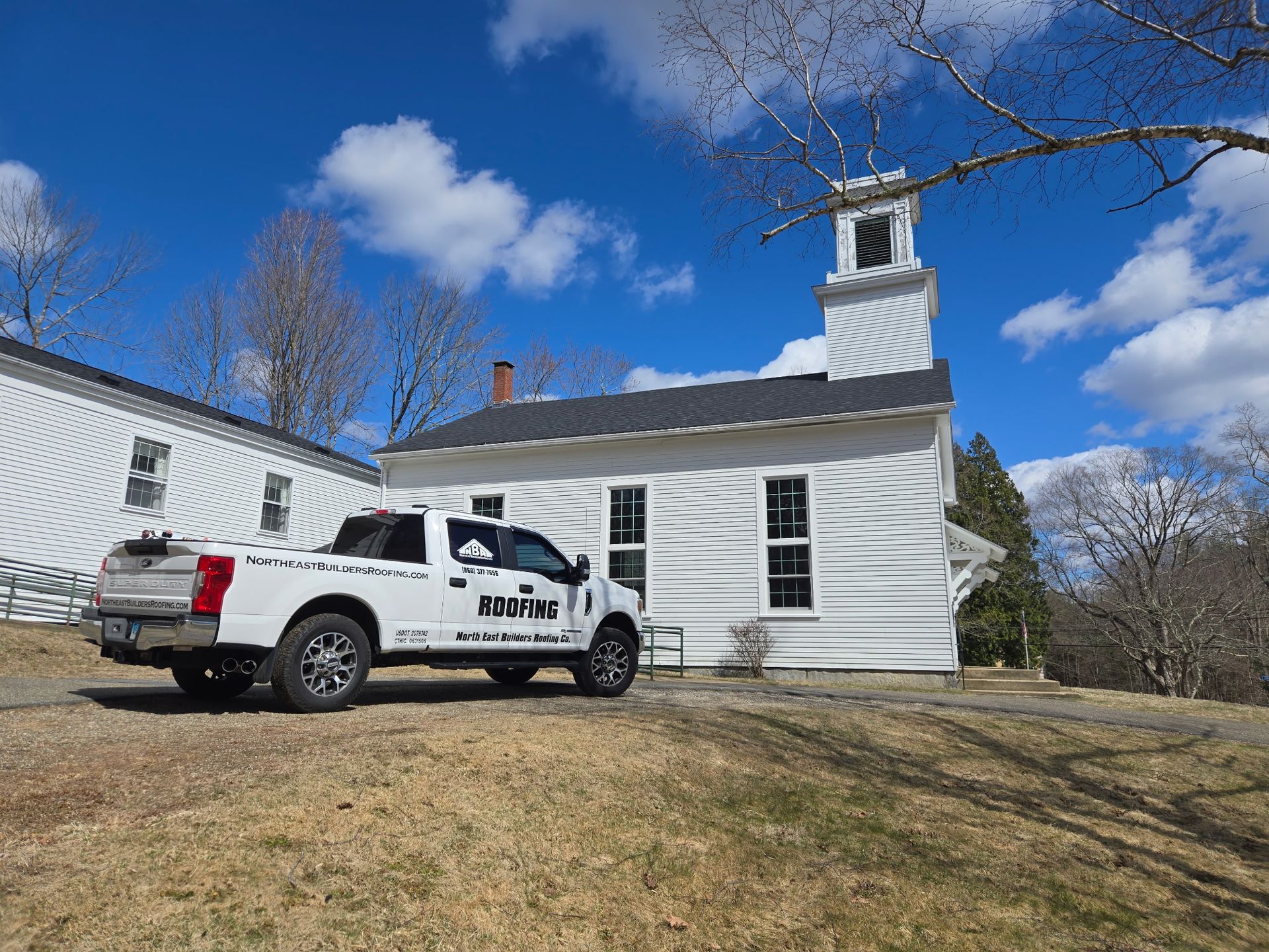 A white truck is parked in front of a white church.