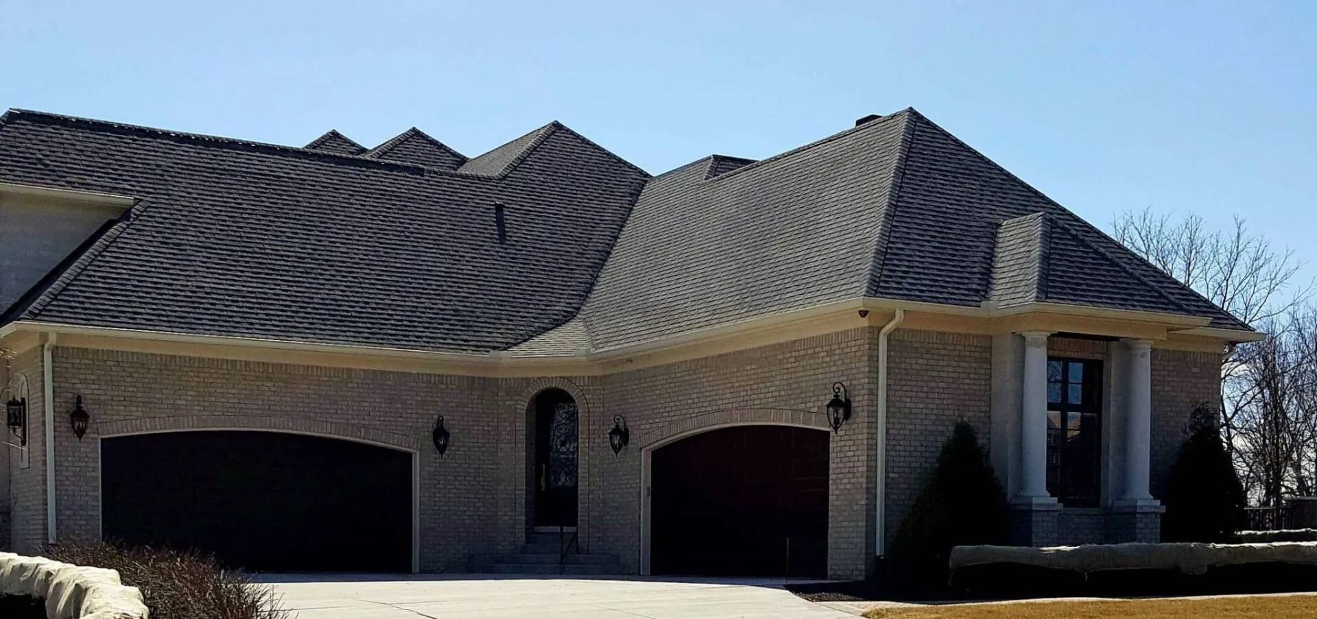 A large brick house with a black roof and two garage doors