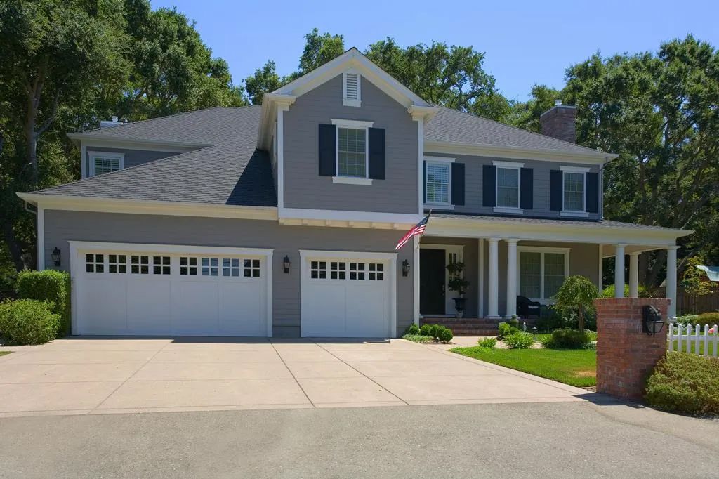 A large house with white garage doors and black shutters