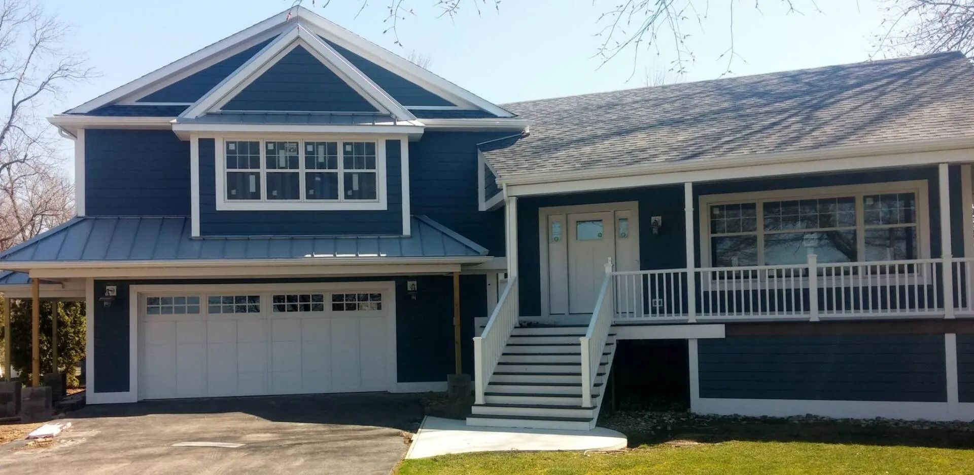 A blue house with a white garage door and stairs
