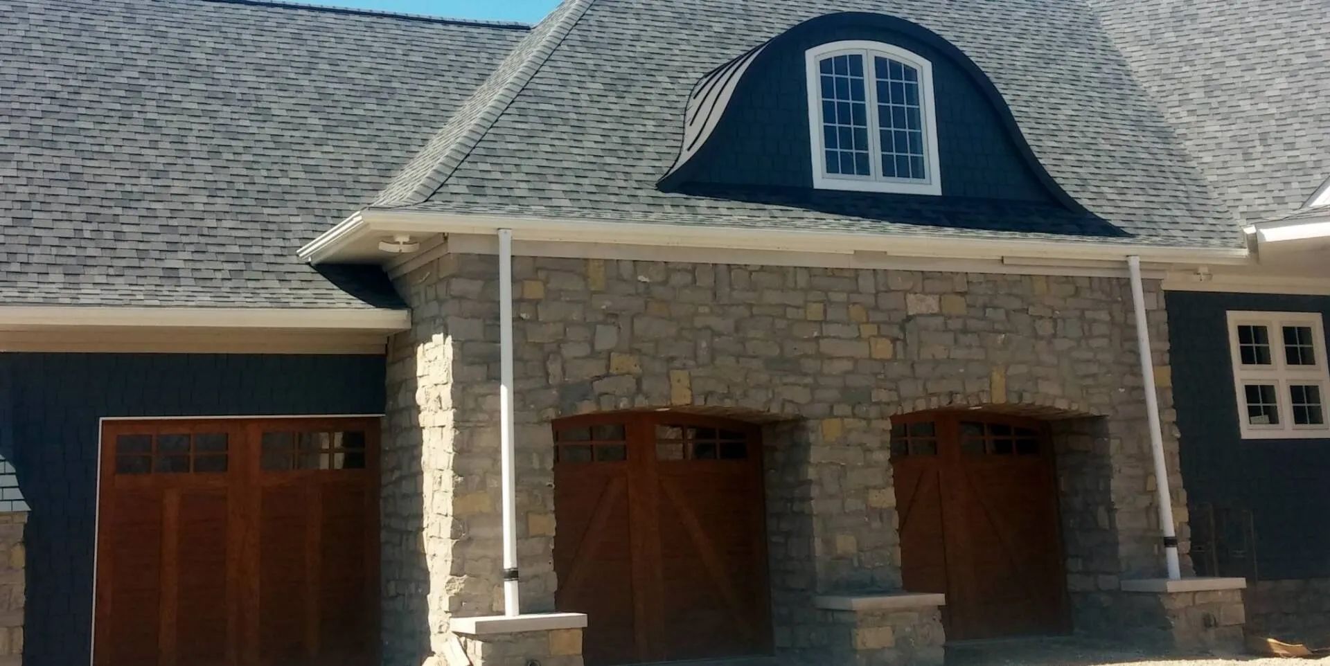 A house with a blue roof and wooden garage doors