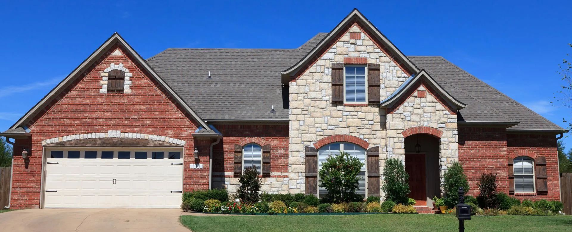 A large brick and stone house with a white garage door