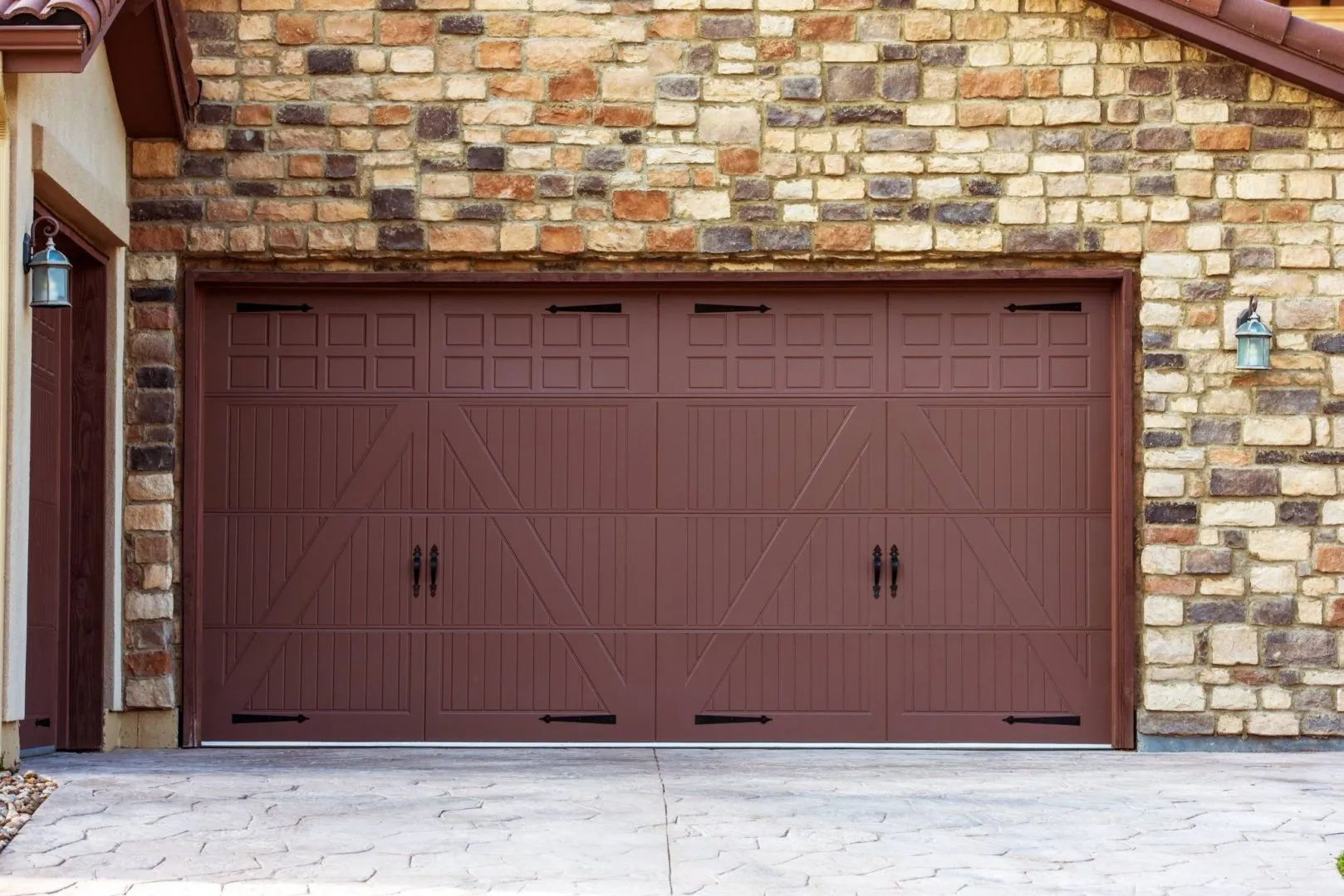 A large brown garage door is sitting in front of a brick building.