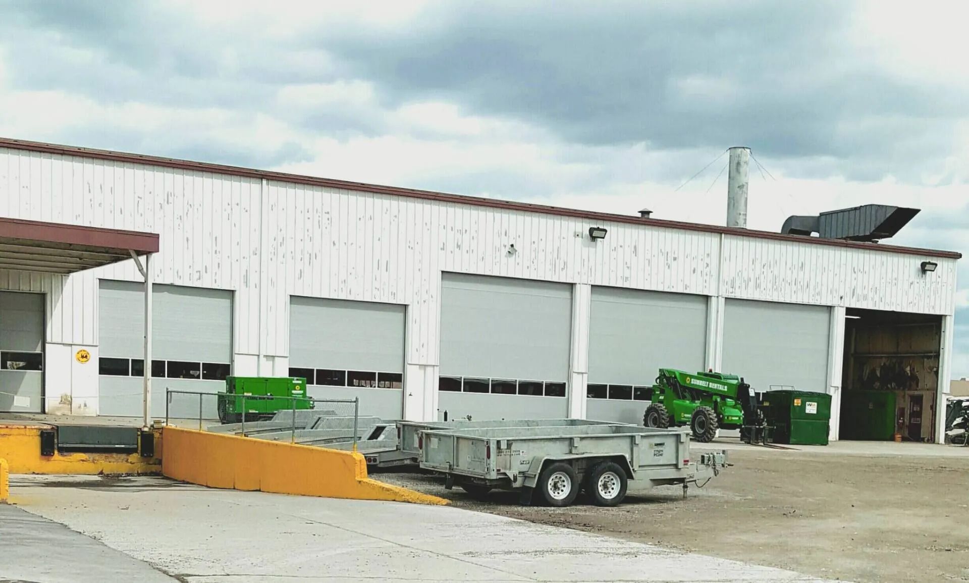 A white building with a trailer parked in front of it.