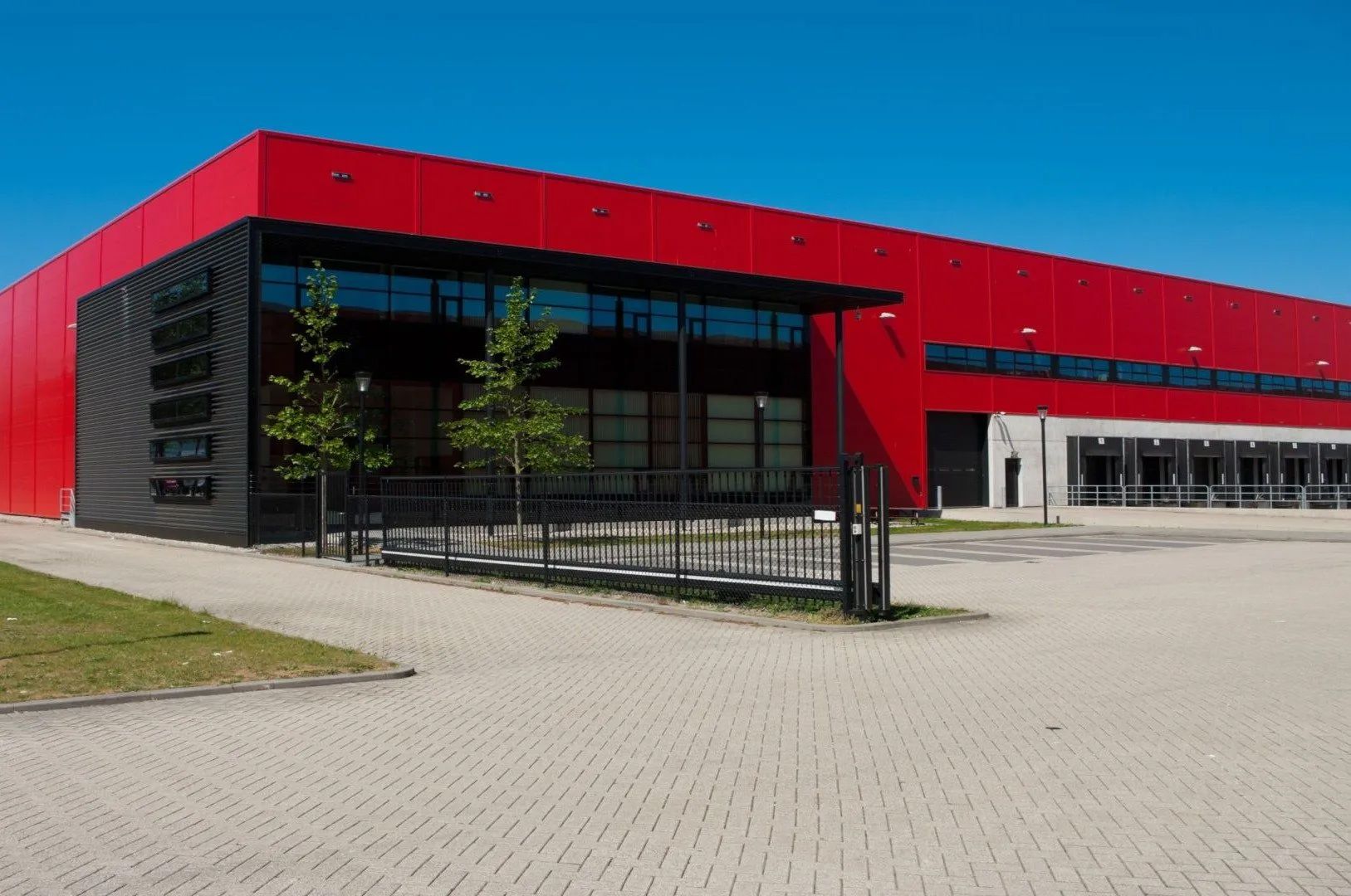 A large red and black building with a fence in front of it.