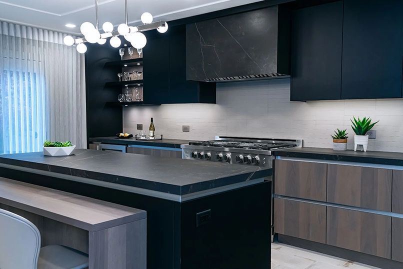 Modern kitchen with dark cabinets, island with seating, stainless steel appliances, and a spherical light fixture.