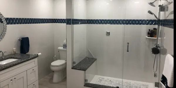 Bathroom with white walls, blue tile border, and a glass shower.