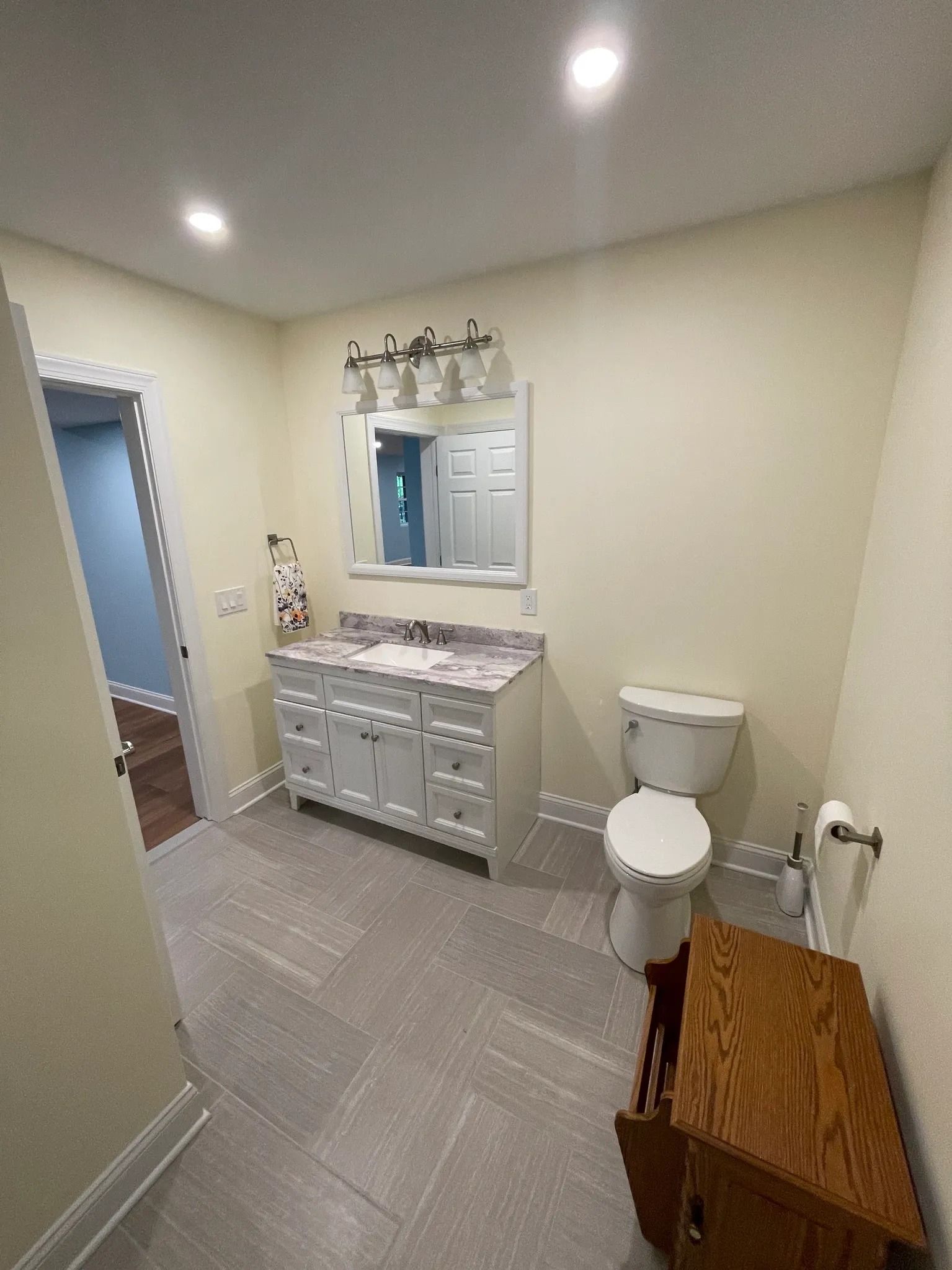 Bathroom with a white vanity, toilet, mirror, and gray floor.