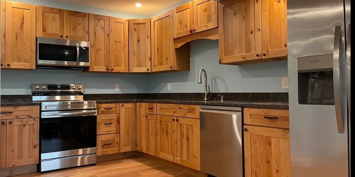 Kitchen with light wood cabinets, stainless steel appliances, and dark countertops.
