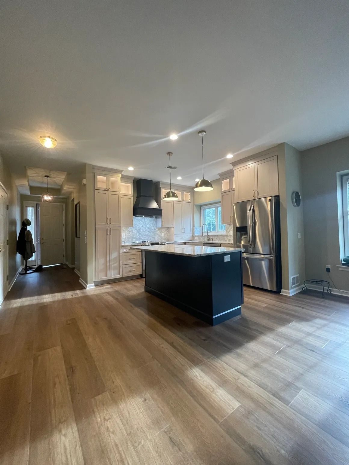 Modern kitchen with wooden floors, island, cabinets, and stainless steel appliances.